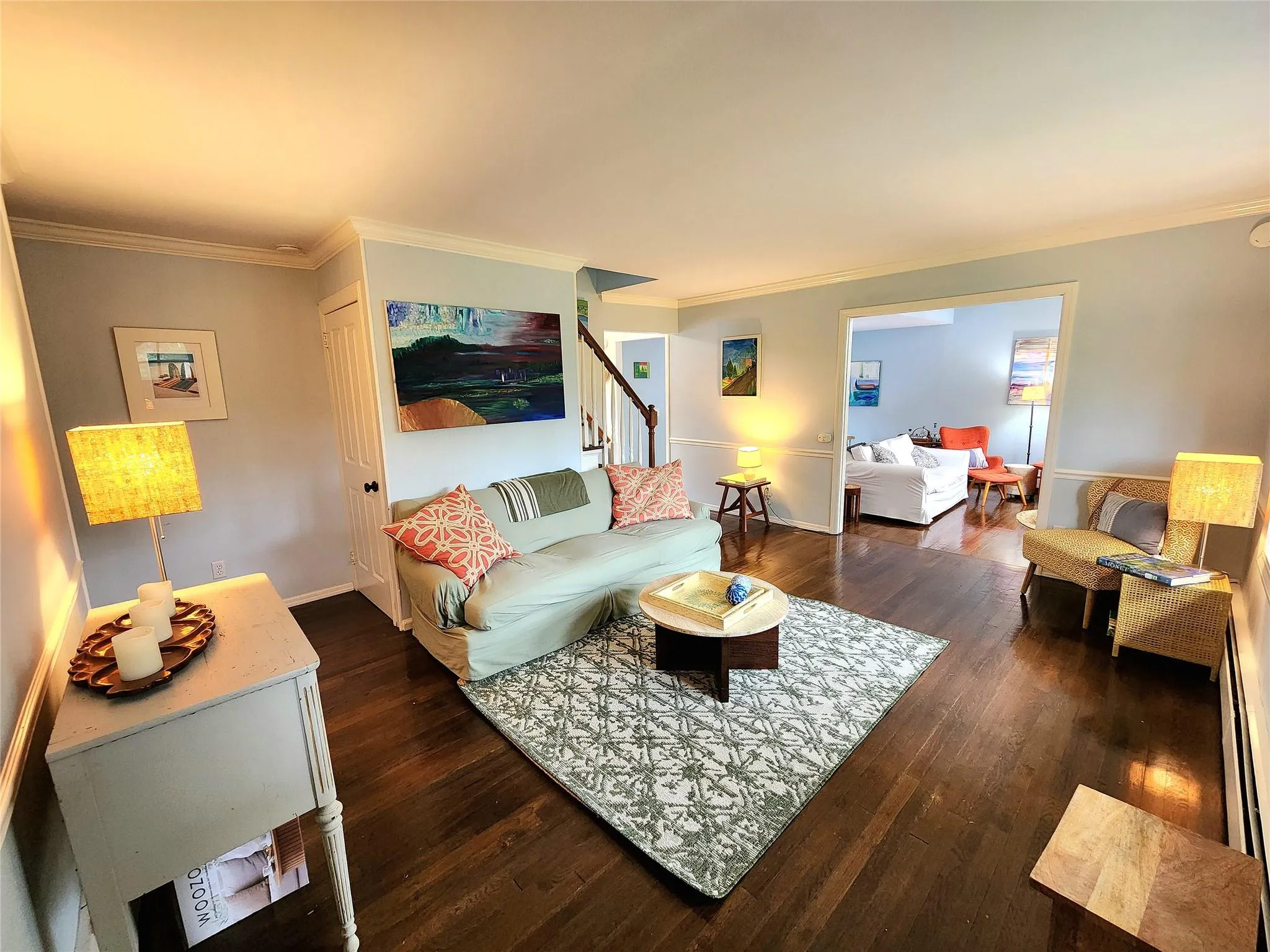 Living area featuring crown molding, dark wood-type flooring, baseboard heating, and stairs Living area featuring crown molding, dark wood-type flooring, baseboard heating, and stairs