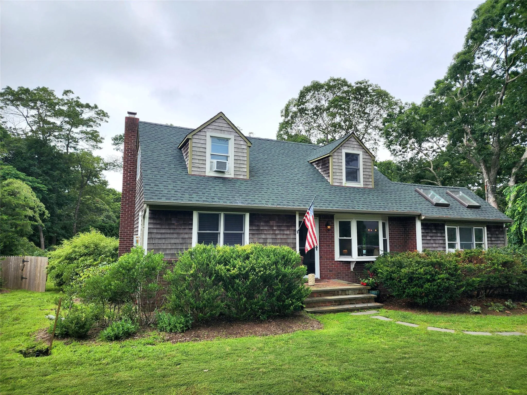 Cape cod home featuring a shingled roof. Cape cod home featuring a shingled roof.