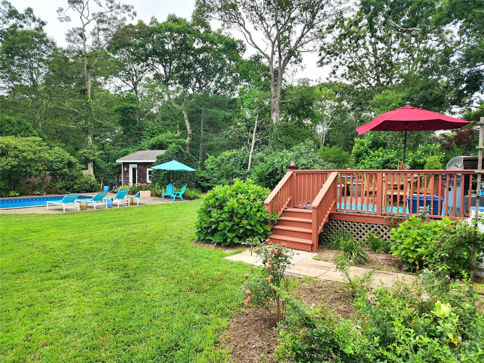 View of grassy yard with an outdoor pool, a deck, an outdoor structure, and view of scattered trees View of grassy yard with an outdoor pool, a deck, an outdoor structure, and view of scattered trees