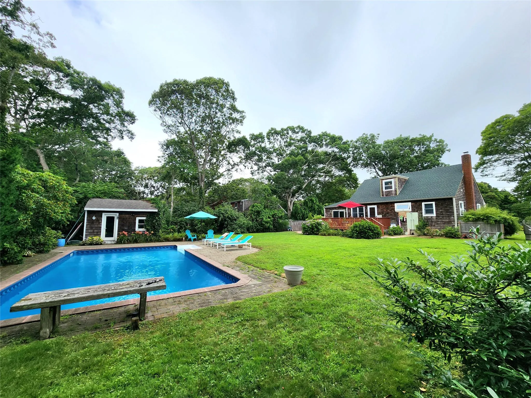 Swimming pool featuring an outdoor structure, a yard, a patio area, and view of scattered trees Swimming pool featuring an outdoor structure, a yard, a patio area, and view of scattered trees
