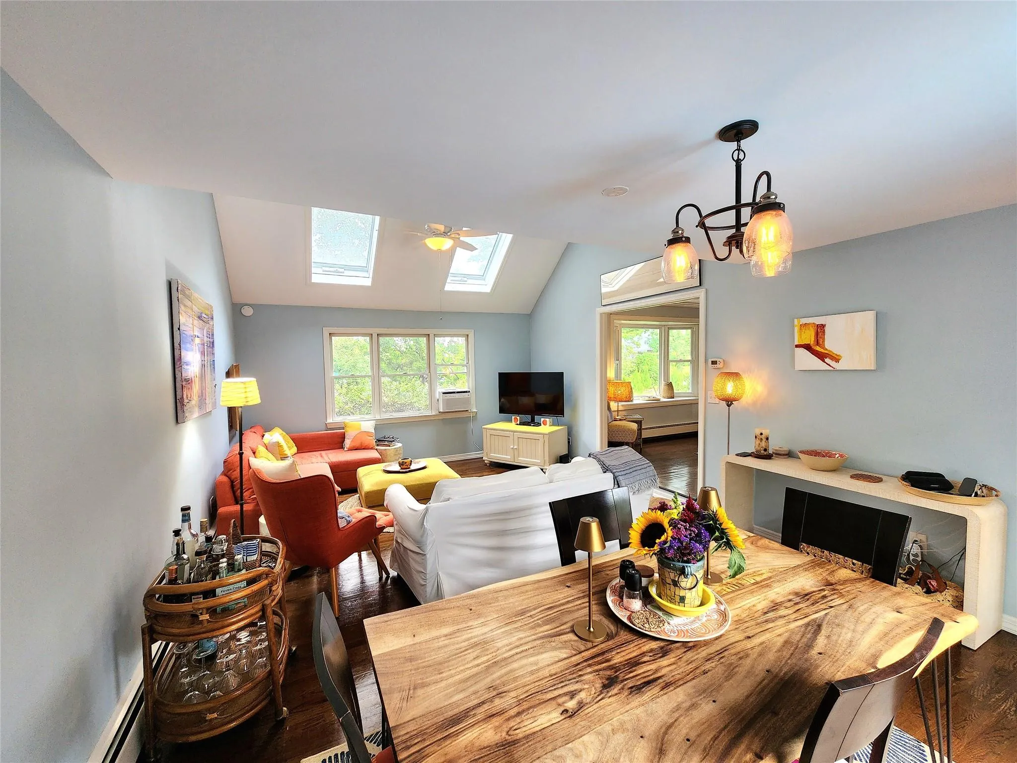 Dining area featuring a skylight, wood finished floors, healthy amount of natural light, vaulted ceiling, and baseboard heating Dining area featuring a skylight, wood finished floors, healthy amount of natural light, vaulted ceiling, and baseboard heating