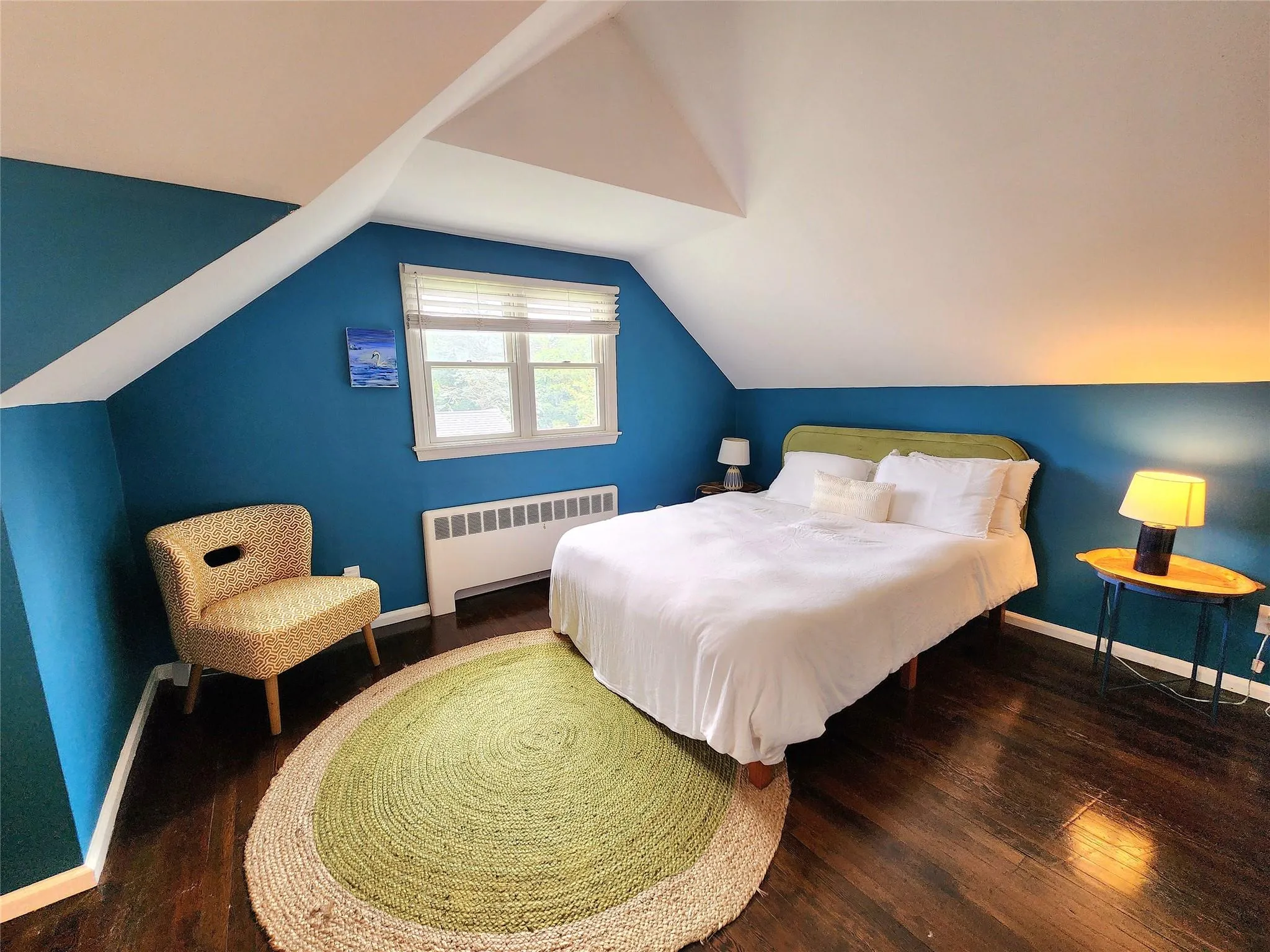 Bedroom featuring radiator heating unit, wood finished floors, and vaulted ceiling Bedroom featuring radiator heating unit, wood finished floors, and vaulted ceiling