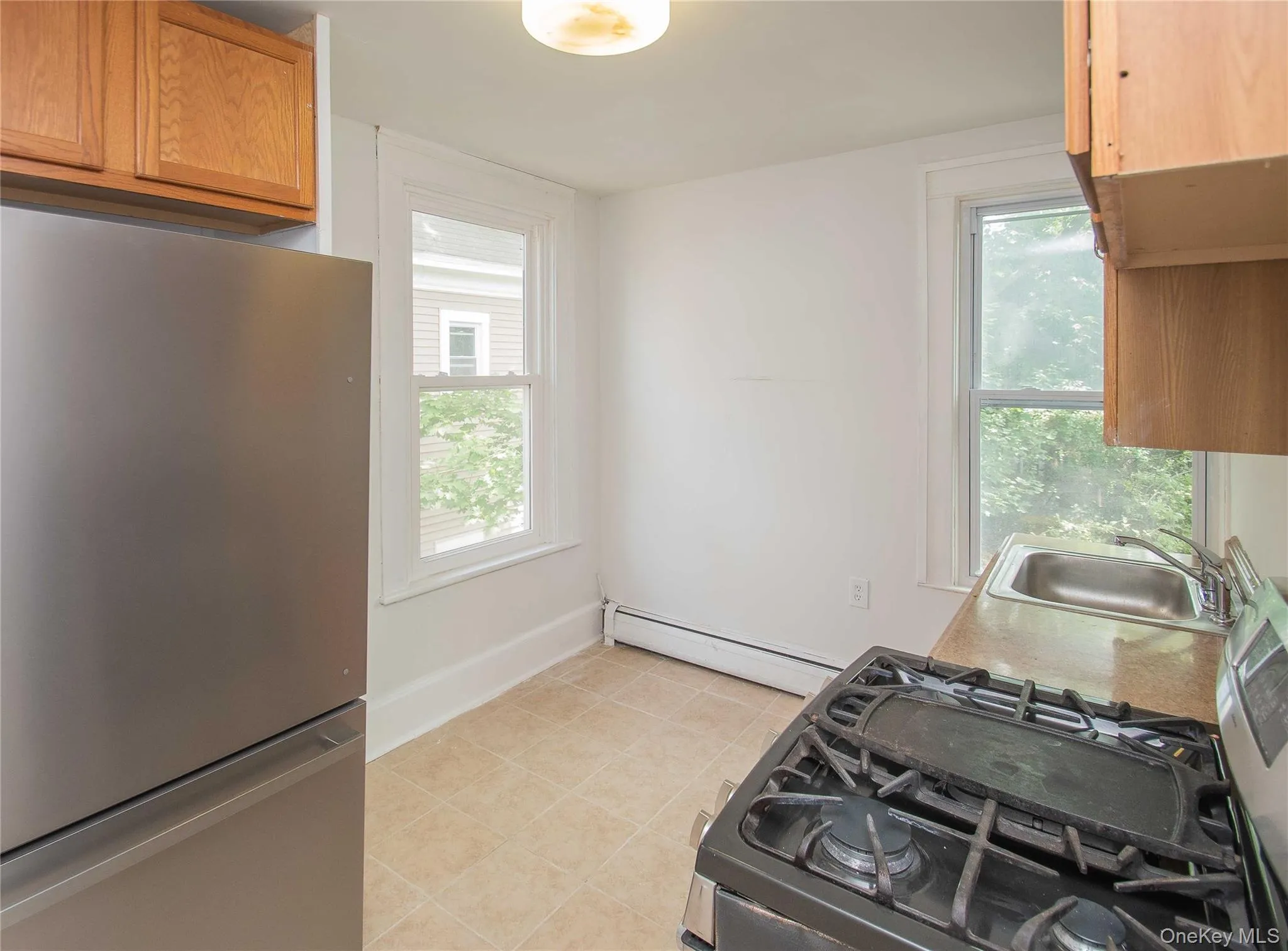 Kitchen with freestanding refrigerator, gas stove, baseboard heating, and healthy amount of natural light Kitchen with freestanding refrigerator, gas stove, baseboard heating, and healthy amount of natural light