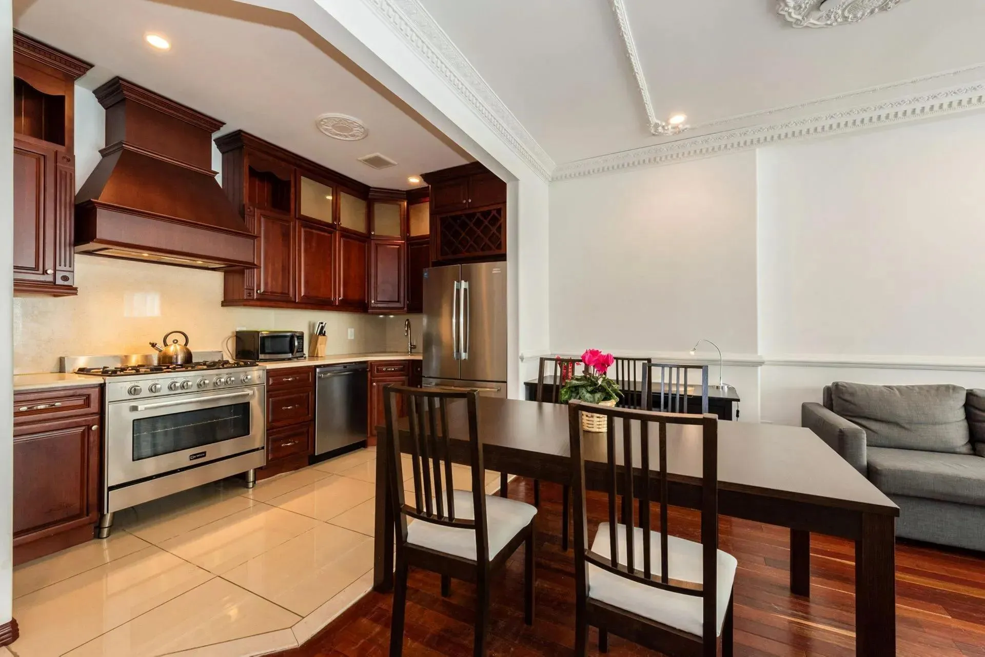 Kitchen featuring appliances with stainless steel finishes, custom exhaust hood, dark brown cabinets, light countertops, and ornamental molding Kitchen featuring appliances with stainless steel finishes, custom exhaust hood, dark brown cabinets, light countertops, and ornamental molding