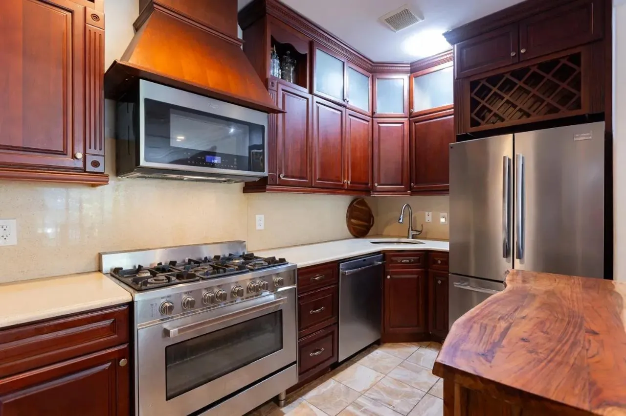 Kitchen with stainless steel appliances, light countertops, custom exhaust hood, and glass insert cabinets Kitchen with stainless steel appliances, light countertops, custom exhaust hood, and glass insert cabinets