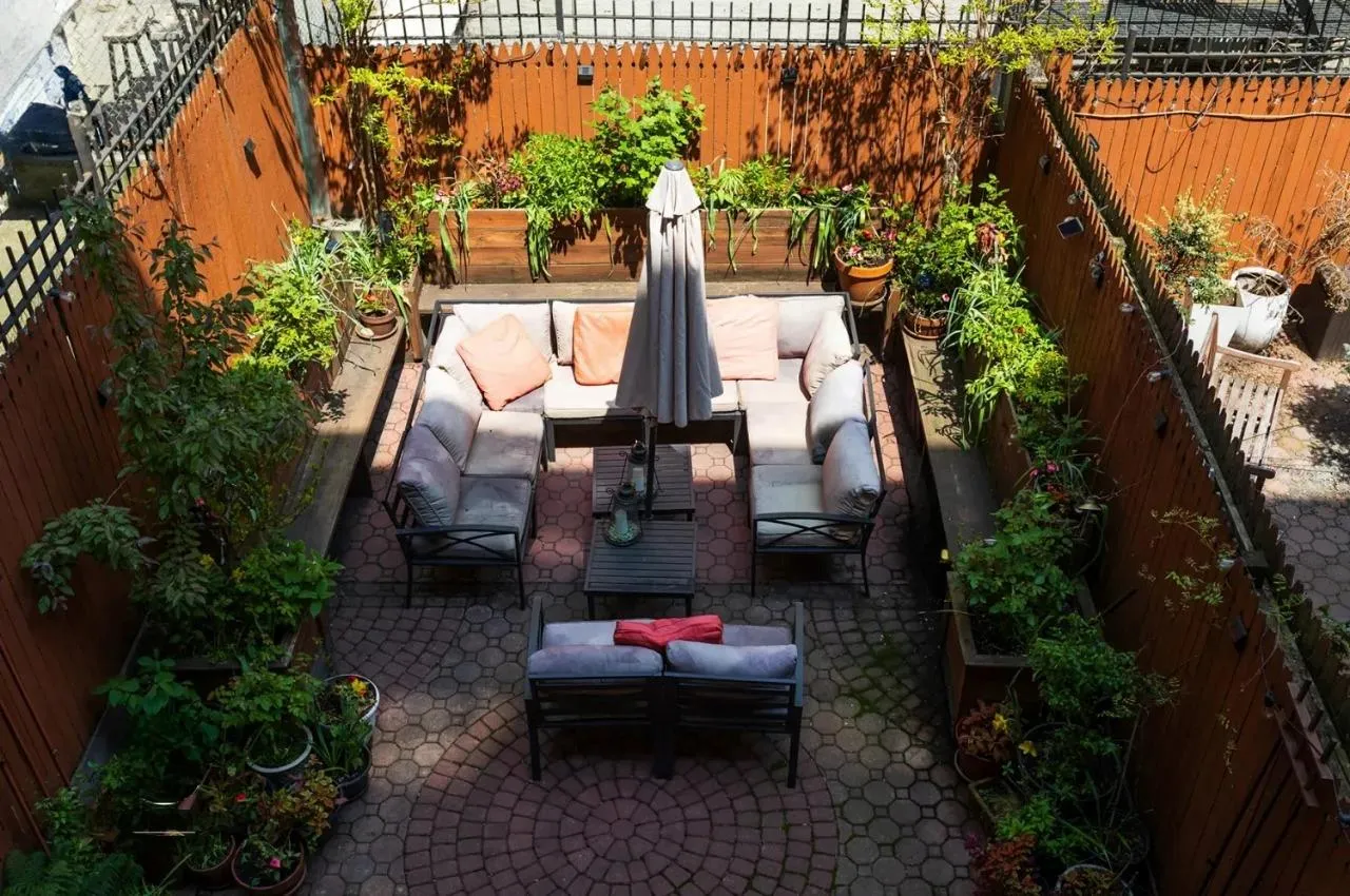 Fenced backyard featuring an outdoor hangout area, a patio area, and a vegetable garden Fenced backyard featuring an outdoor hangout area, a patio area, and a vegetable garden