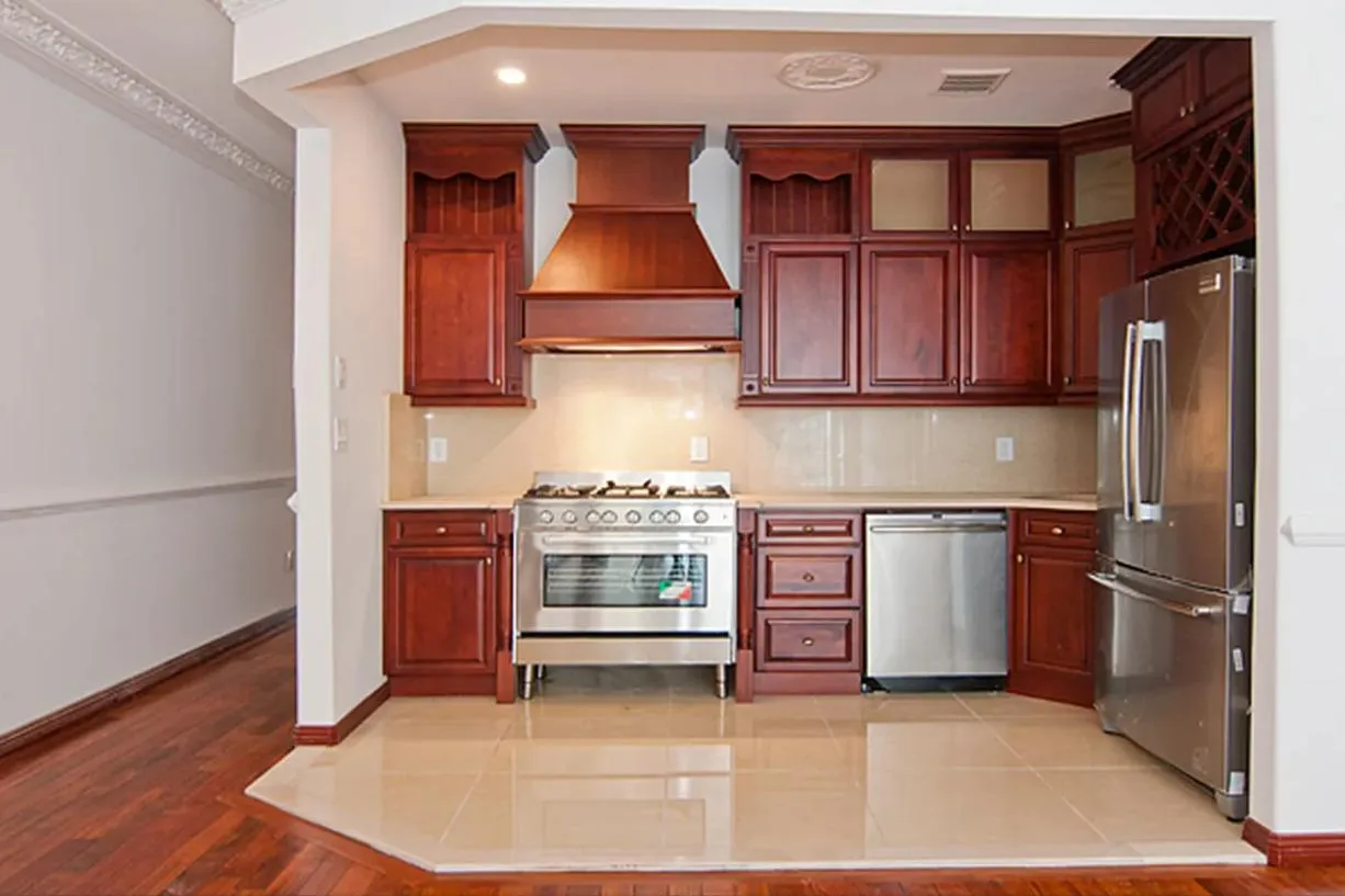 Kitchen with reddish brown cabinets, appliances with stainless steel finishes, light countertops, light wood-type flooring, and recessed lighting Kitchen with reddish brown cabinets, appliances with stainless steel finishes, light countertops, light wood-type flooring, and recessed lighting