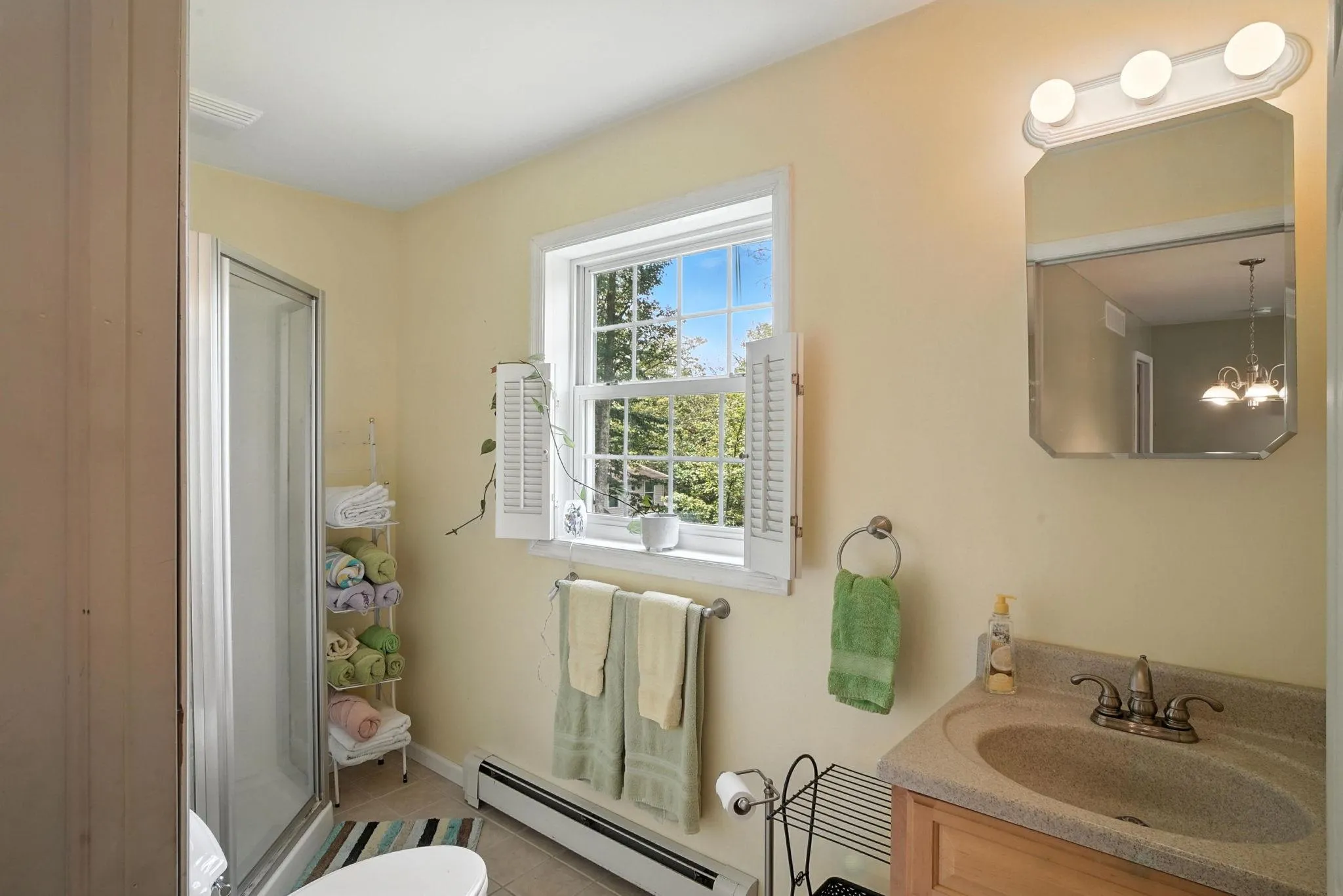 Full bath with a baseboard heating unit, vanity, a stall shower, tile patterned flooring, and a chandelier Full bath with a baseboard heating unit, vanity, a stall shower, tile patterned flooring, and a chandelier