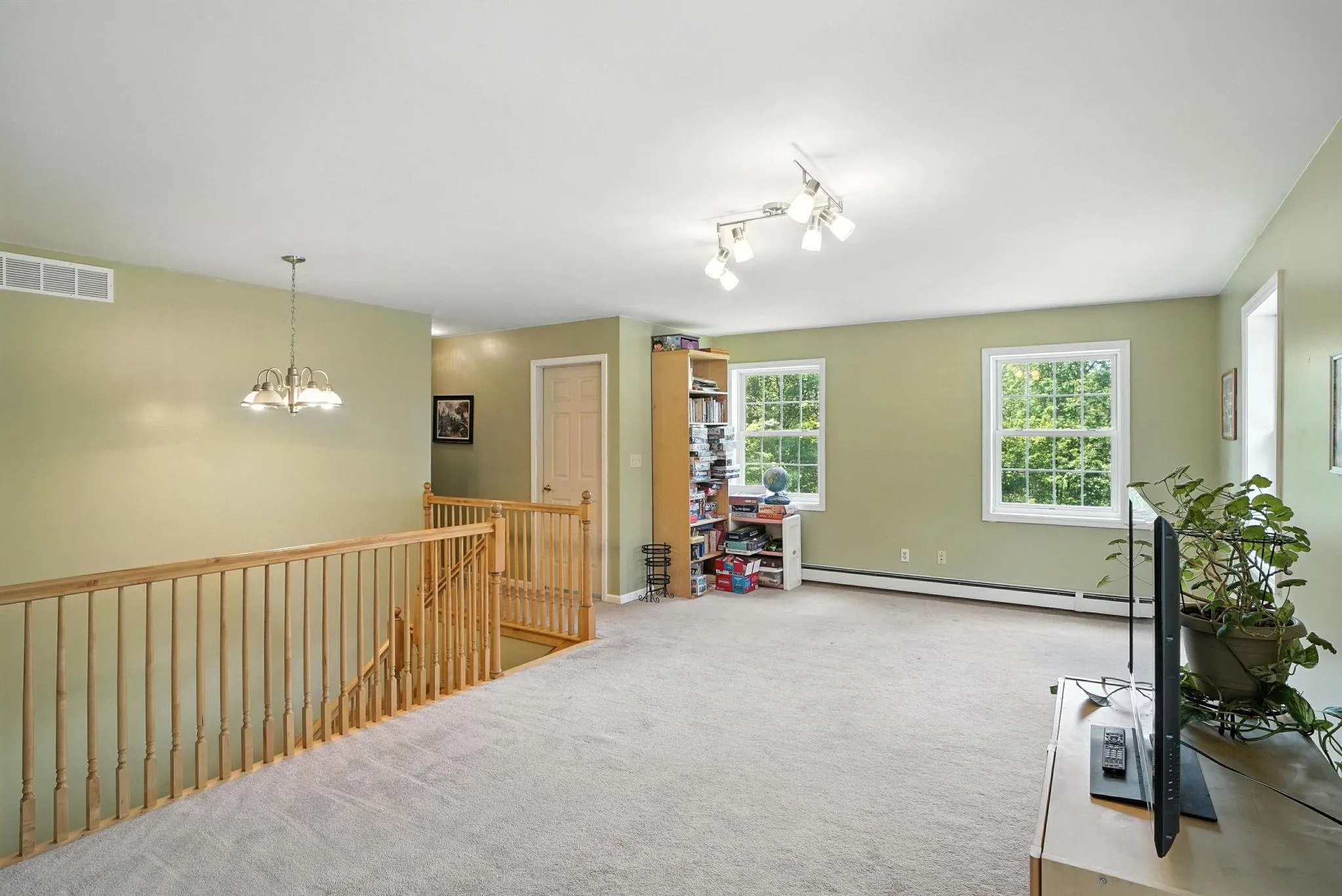 Living area with an upstairs landing, carpet flooring, and a lot of natural light Living area with an upstairs landing, carpet flooring, and a lot of natural light