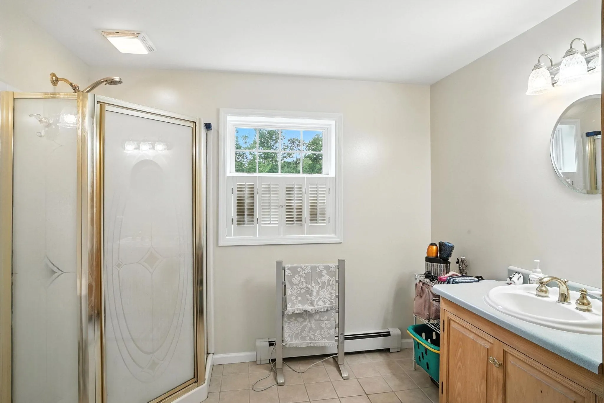 Full bath featuring vanity, a shower stall, tile patterned flooring, and a baseboard heating unit Full bath featuring vanity, a shower stall, tile patterned flooring, and a baseboard heating unit