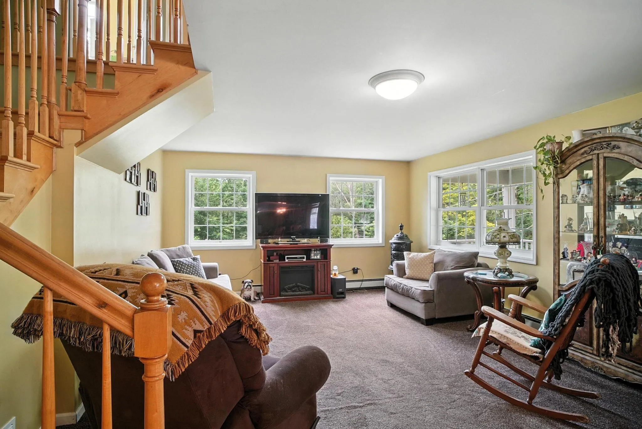 Living room featuring carpet floors, stairs, and a baseboard radiator Living room featuring carpet floors, stairs, and a baseboard radiator