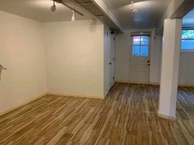 Below grade area featuring track lighting and wood finished floors Below grade area featuring track lighting and wood finished floors