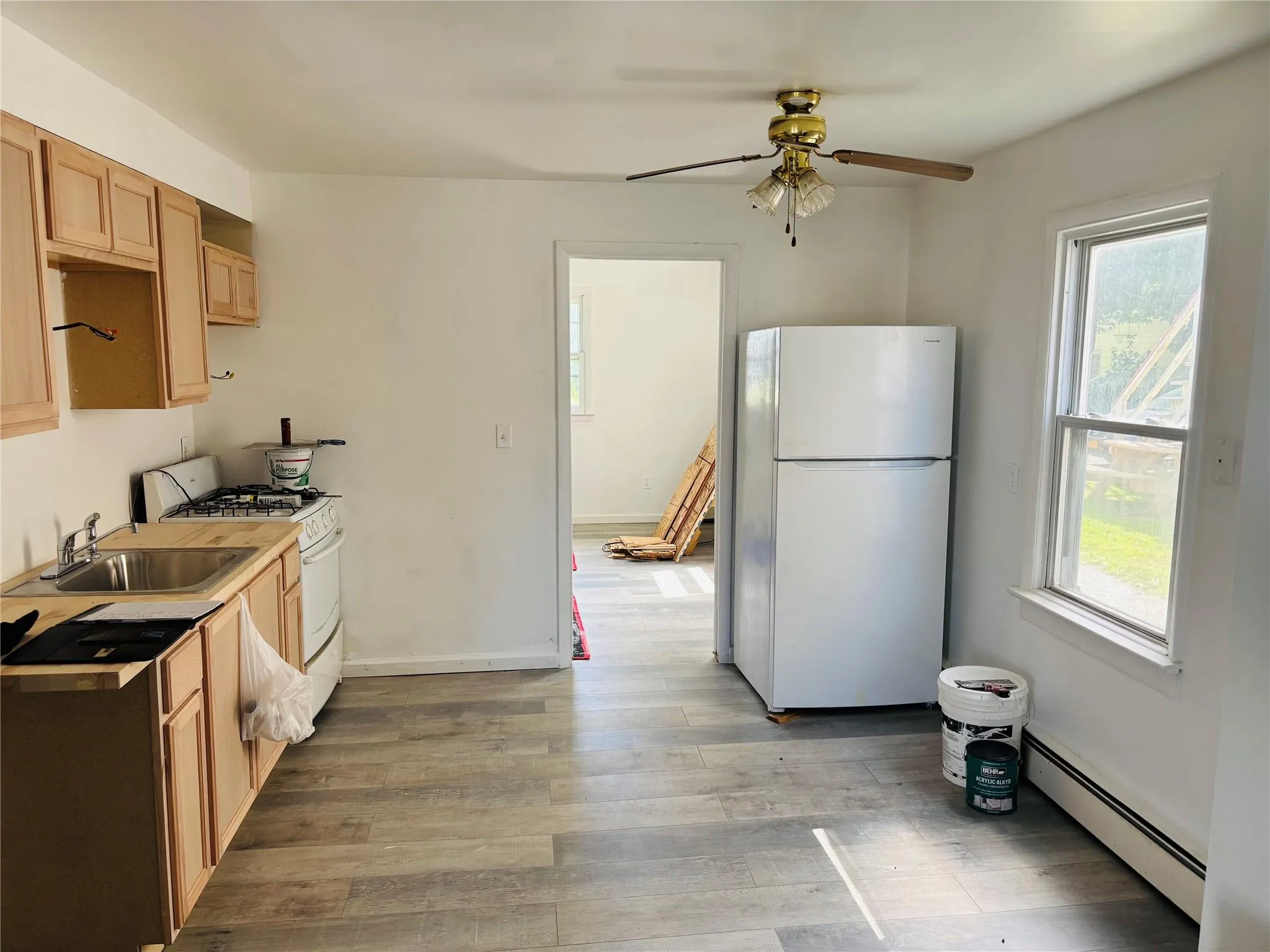 Kitchen with white appliances, baseboard heating, plenty of natural light, and a ceiling fan Kitchen with white appliances, baseboard heating, plenty of natural light, and a ceiling fan