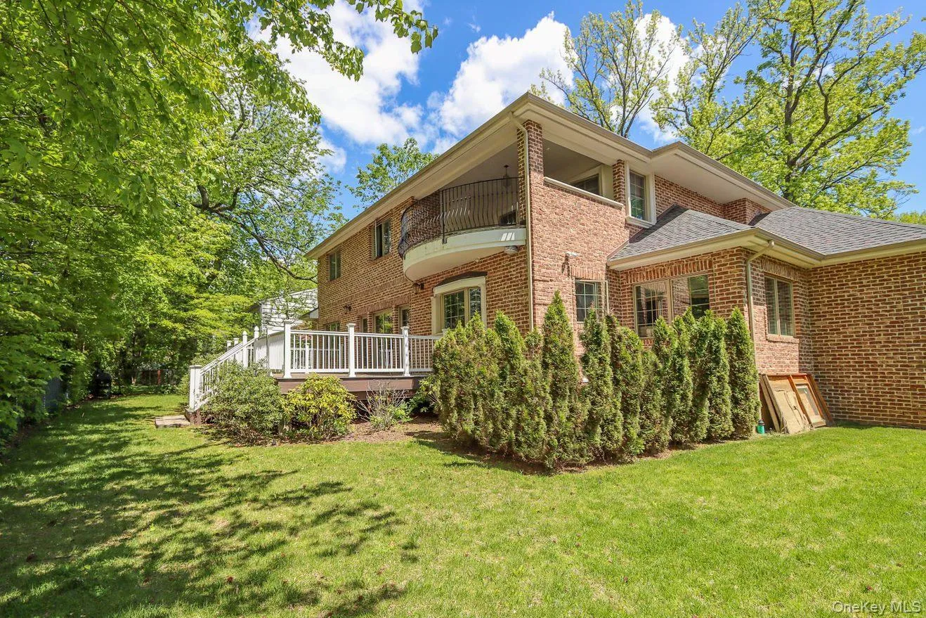 Back of house featuring brick siding, a yard, a shingled roof, and a deck Back of house featuring brick siding, a yard, a shingled roof, and a deck