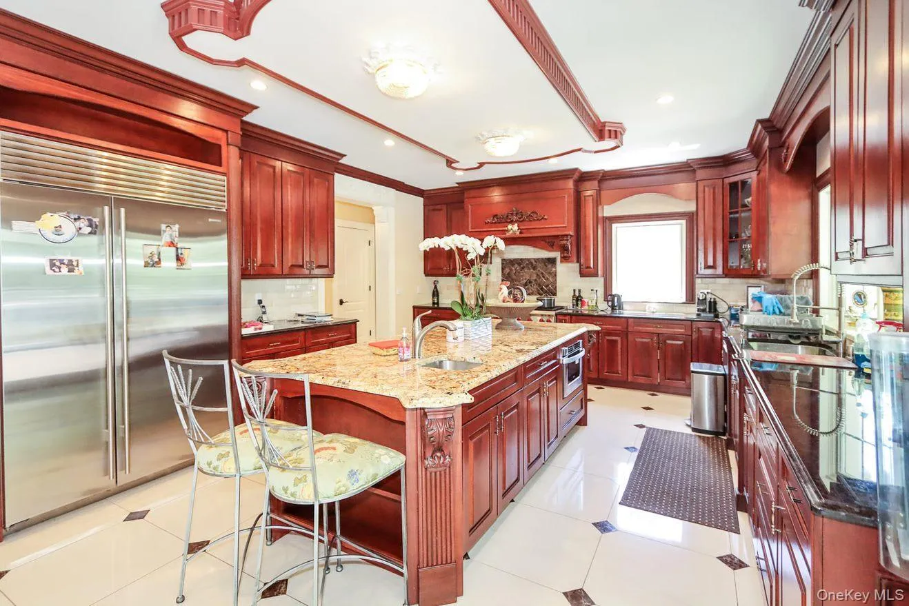 Kitchen with reddish brown cabinets, appliances with stainless steel finishes, tasteful backsplash, light stone counters, and recessed lighting Kitchen with reddish brown cabinets, appliances with stainless steel finishes, tasteful backsplash, light stone counters, and recessed lighting