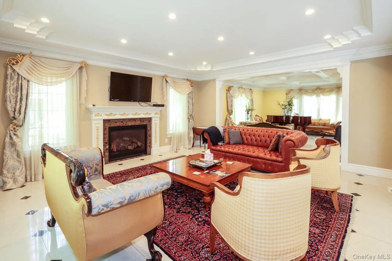 Tiled living room featuring crown molding, a premium fireplace, recessed lighting, and a raised ceiling Tiled living room featuring crown molding, a premium fireplace, recessed lighting, and a raised ceiling
