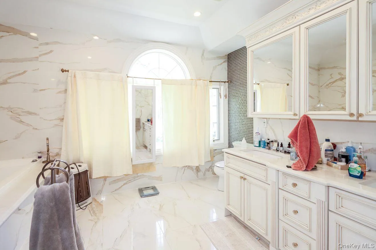 Full bath featuring vanity, a tub with marble appearance, and marble tiled floors Full bath featuring vanity, a tub with marble appearance, and marble tiled floors