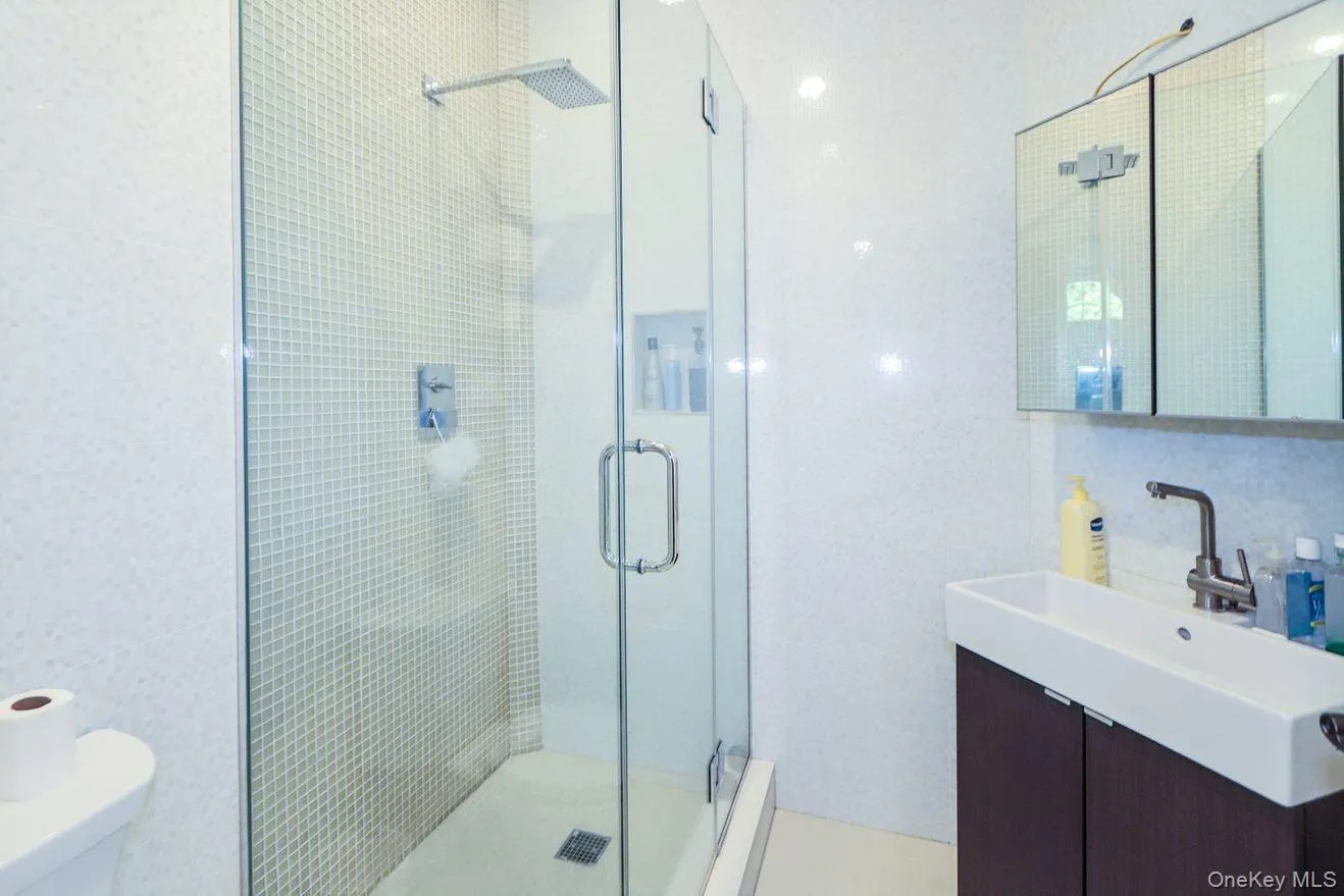 Bathroom featuring tile walls, a stall shower, vanity, and a baseboard radiator Bathroom featuring tile walls, a stall shower, vanity, and a baseboard radiator