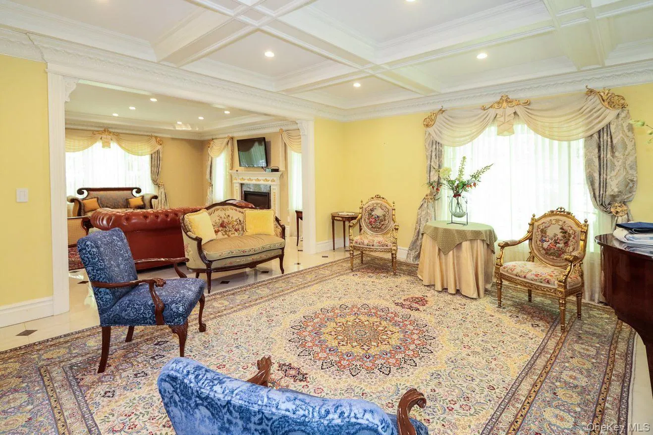 Living area featuring ornamental molding, beam ceiling, a fireplace, coffered ceiling, and recessed lighting Living area featuring ornamental molding, beam ceiling, a fireplace, coffered ceiling, and recessed lighting