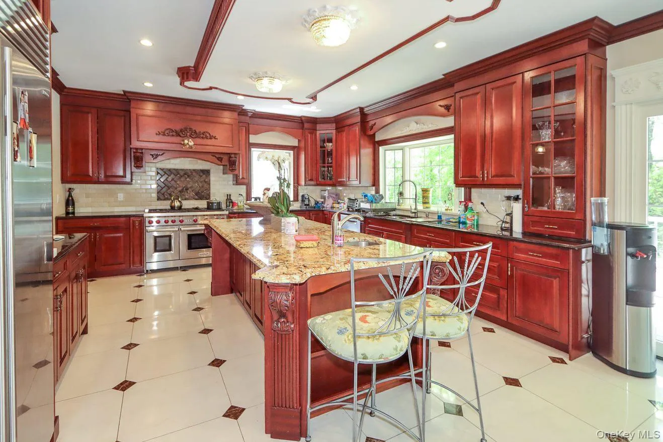 Kitchen with dark brown cabinets, a center island with sink, high end appliances, decorative backsplash, and recessed lighting Kitchen with dark brown cabinets, a center island with sink, high end appliances, decorative backsplash, and recessed lighting