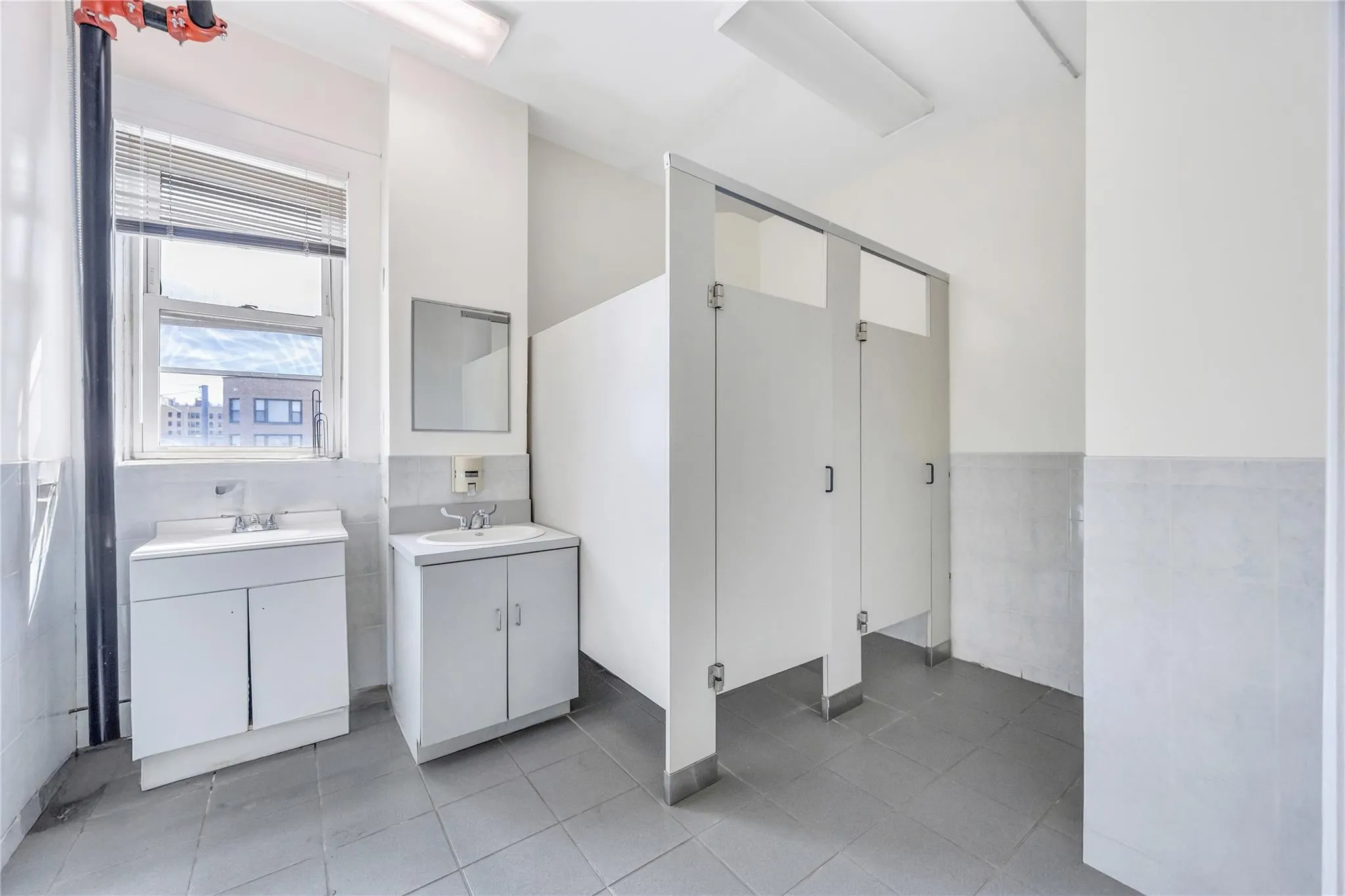 Bathroom with tile walls, two vanities, tile patterned floors, and wainscoting Bathroom with tile walls, two vanities, tile patterned floors, and wainscoting