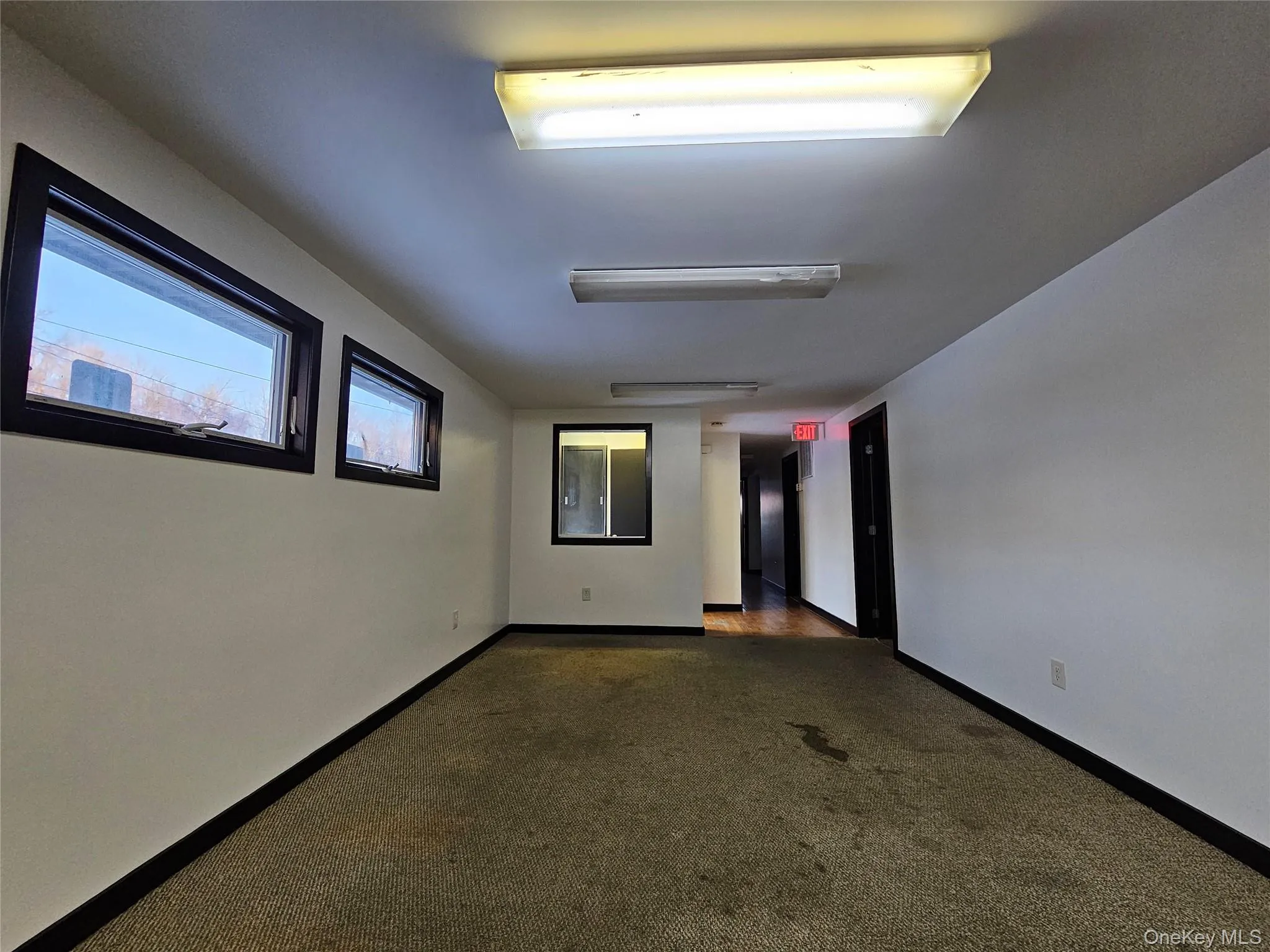 Spare room featuring baseboards and dark colored carpet Spare room featuring baseboards and dark colored carpet