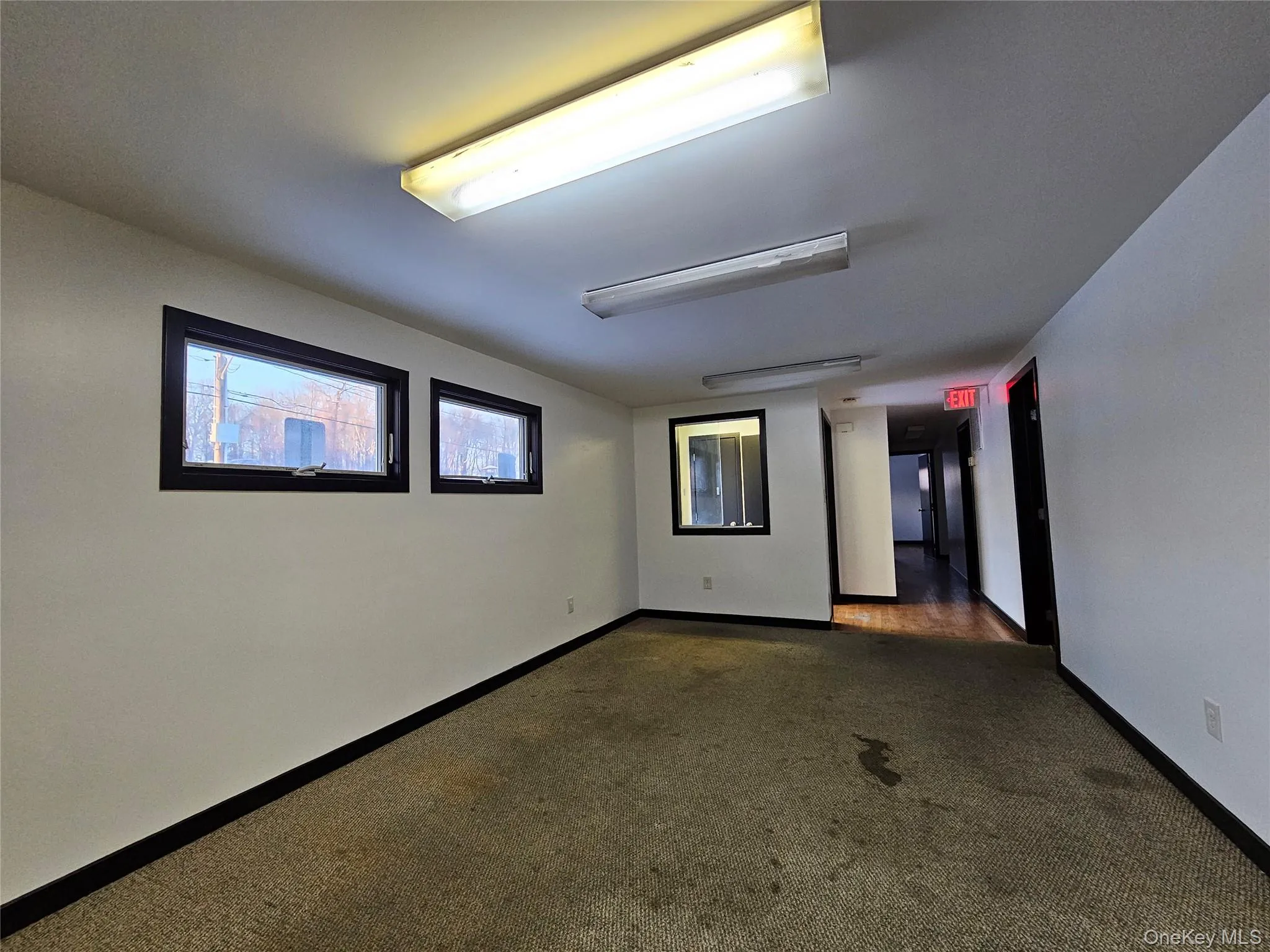 Spare room featuring baseboards and dark colored carpet Spare room featuring baseboards and dark colored carpet