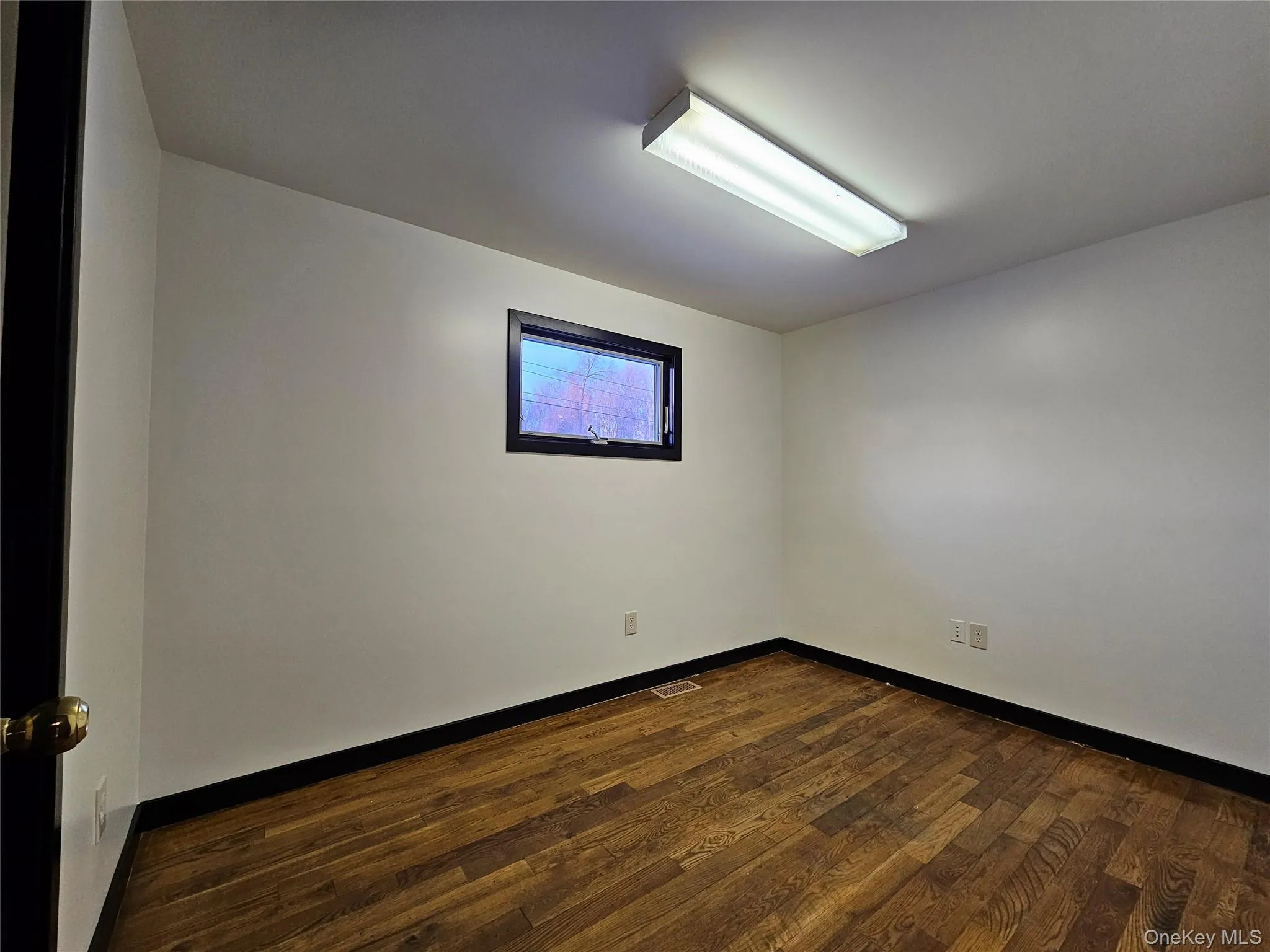 Unfurnished room with dark wood-type flooring and baseboards Unfurnished room with dark wood-type flooring and baseboards