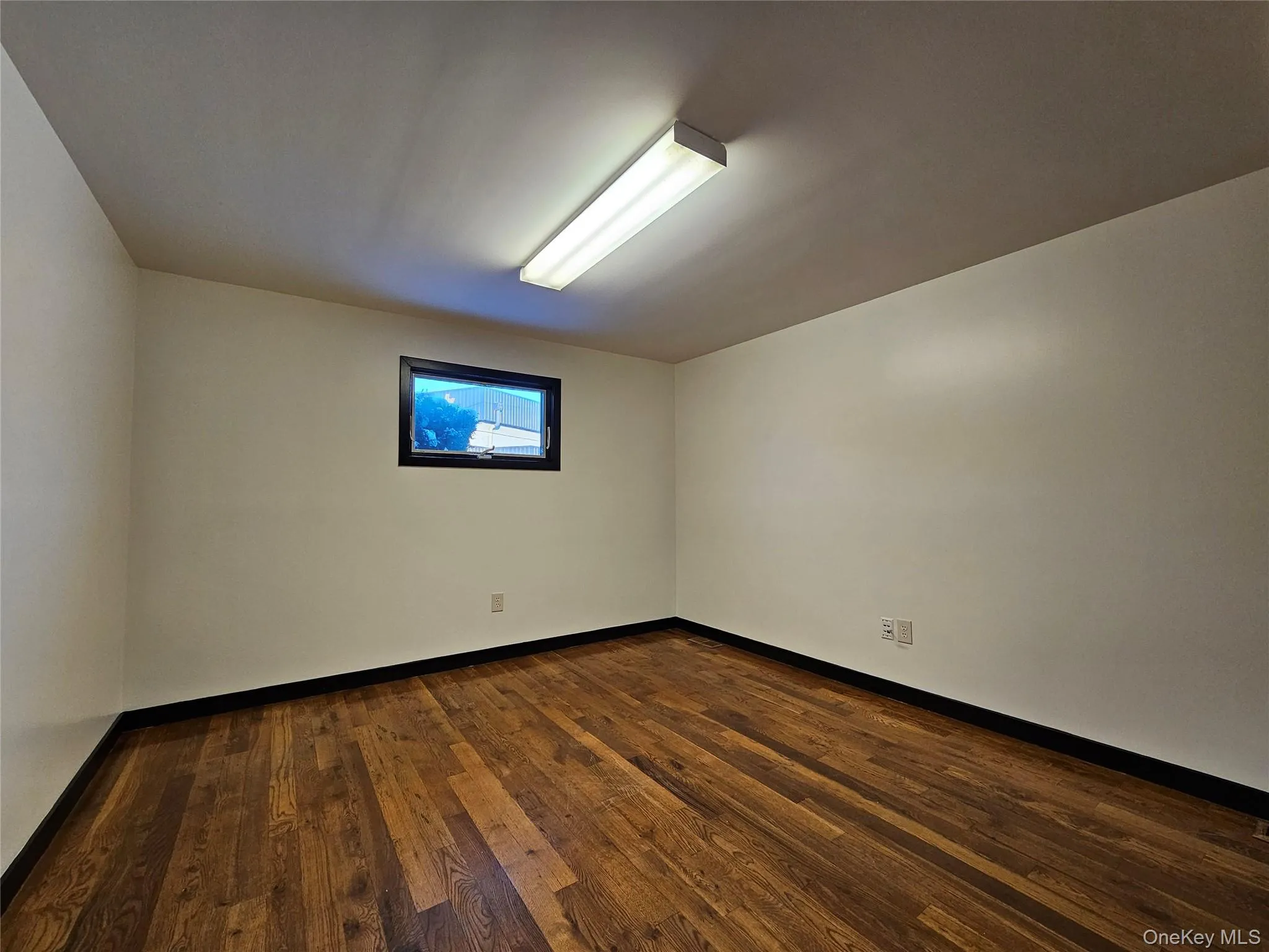Unfurnished room featuring dark wood-type flooring and baseboards Unfurnished room featuring dark wood-type flooring and baseboards