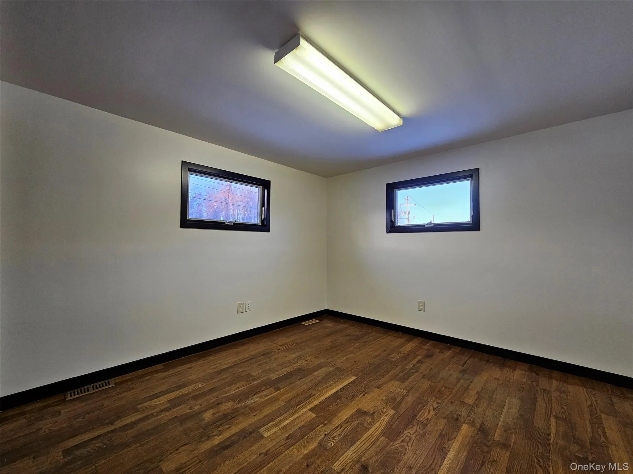 Spare room featuring dark wood-style flooring and baseboards Spare room featuring dark wood-style flooring and baseboards