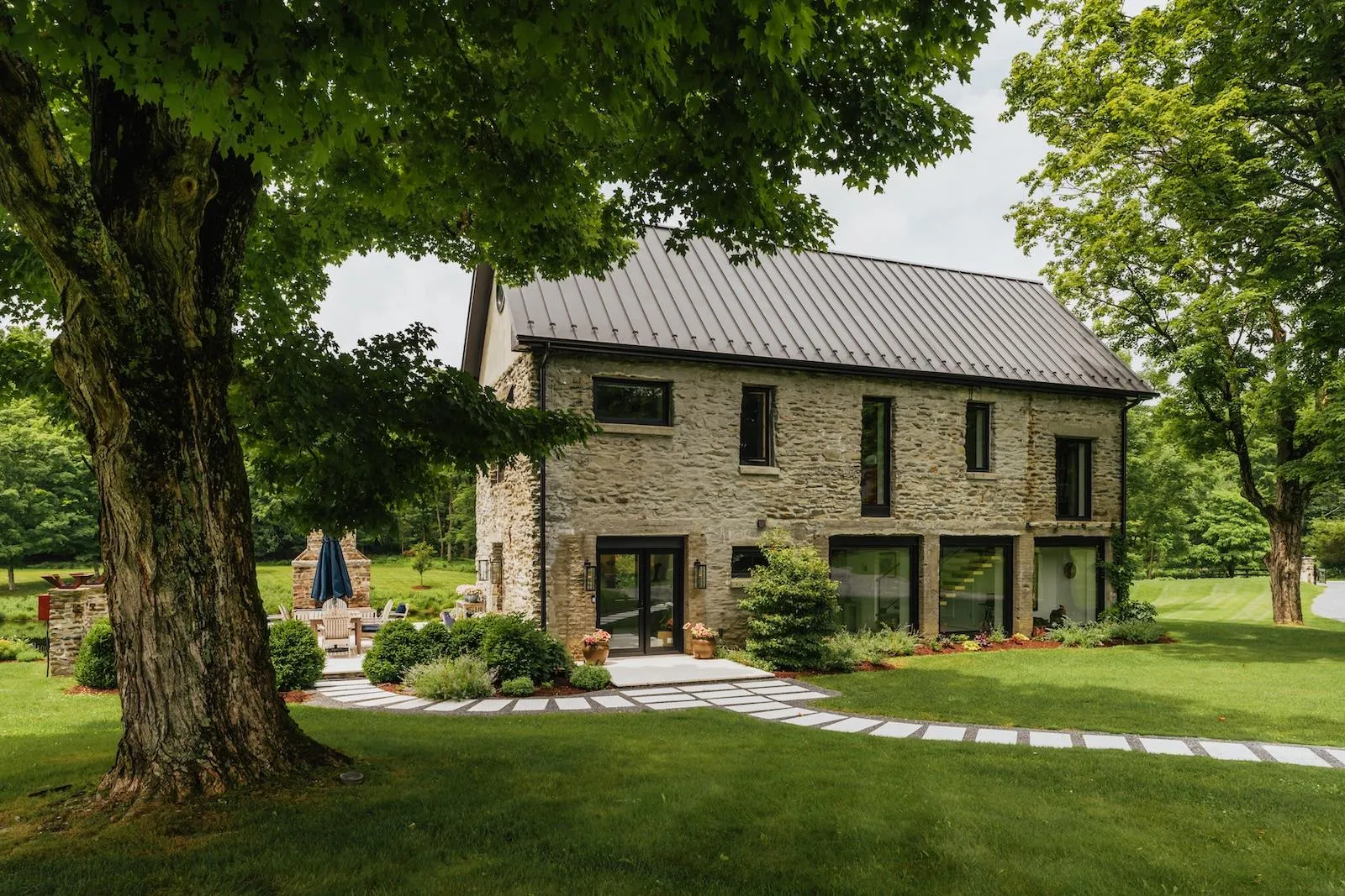 Back of property featuring stone siding, a standing seam roof, a metal roof, a yard, and french doors Back of property featuring stone siding, a standing seam roof, a metal roof, a yard, and french doors