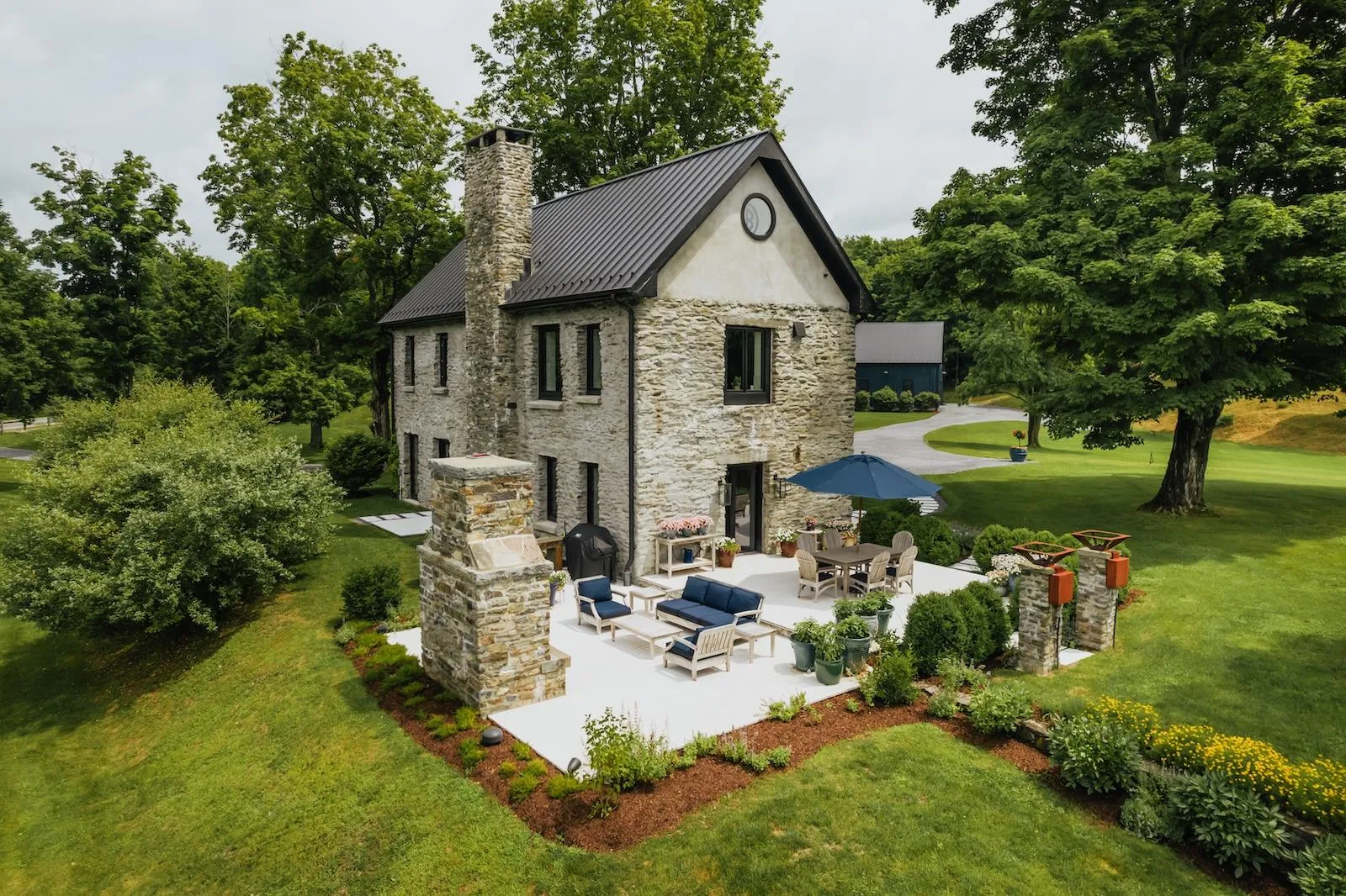 Back of house with stone siding, a patio, a lawn, a standing seam roof, and a metal roof Back of house with stone siding, a patio, a lawn, a standing seam roof, and a metal roof