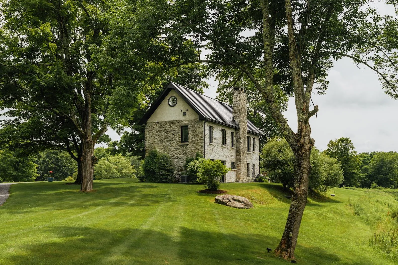 View of side of property featuring a metal roof, a yard, a chimney, and stone siding View of side of property featuring a metal roof, a yard, a chimney, and stone siding