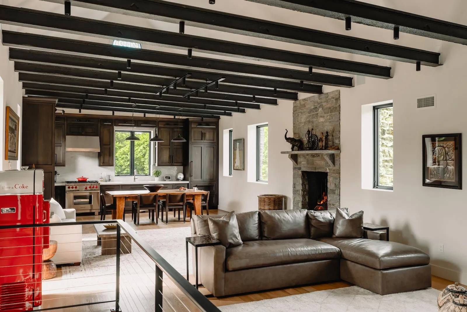 Living area with light wood-style floors, a stone fireplace, and beam ceiling Living area with light wood-style floors, a stone fireplace, and beam ceiling