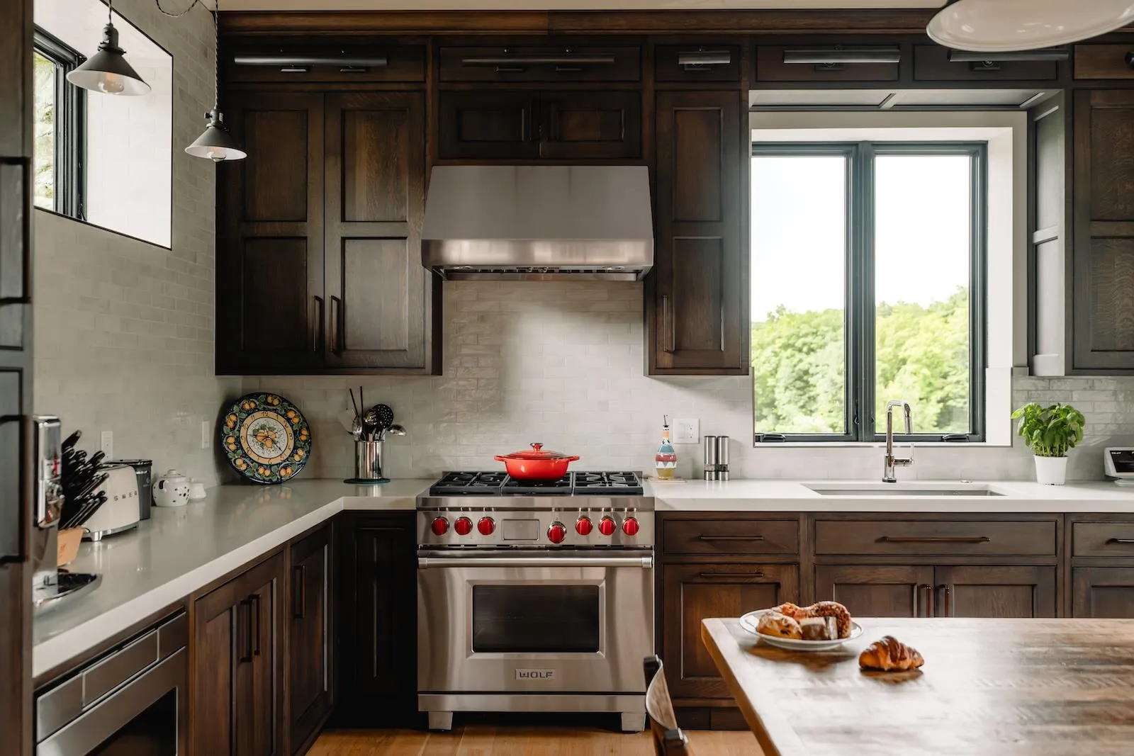 Kitchen with appliances with stainless steel finishes, wall chimney range hood, decorative backsplash, light countertops, and healthy amount of natural light Kitchen with appliances with stainless steel finishes, wall chimney range hood, decorative backsplash, light countertops, and healthy amount of natural light