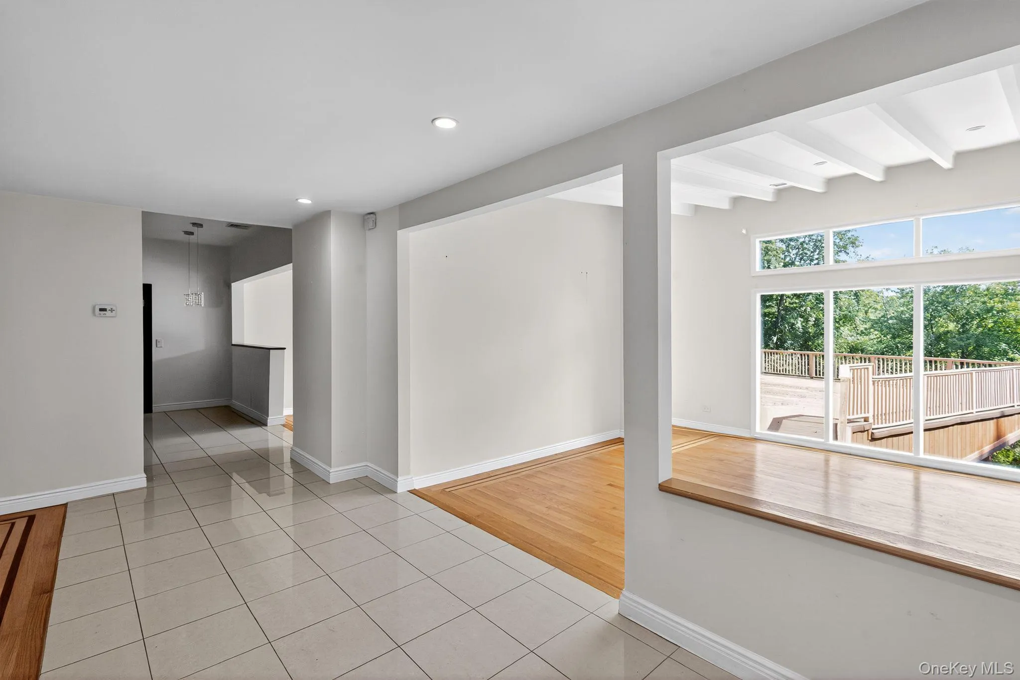 Empty room featuring light tile patterned floors, beam ceiling, and recessed lighting Empty room featuring light tile patterned floors, beam ceiling, and recessed lighting