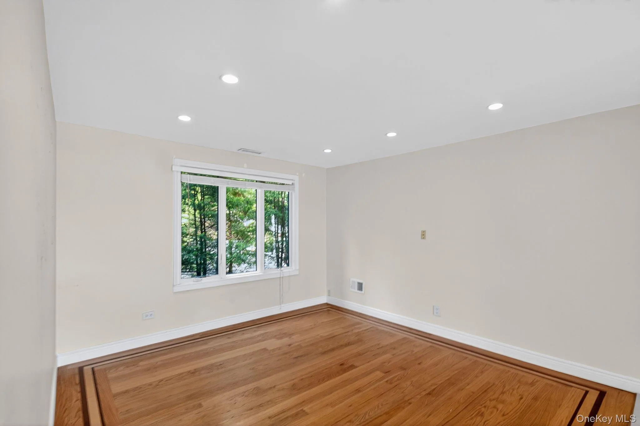 Empty room with wood finished floors and recessed lighting Empty room with wood finished floors and recessed lighting