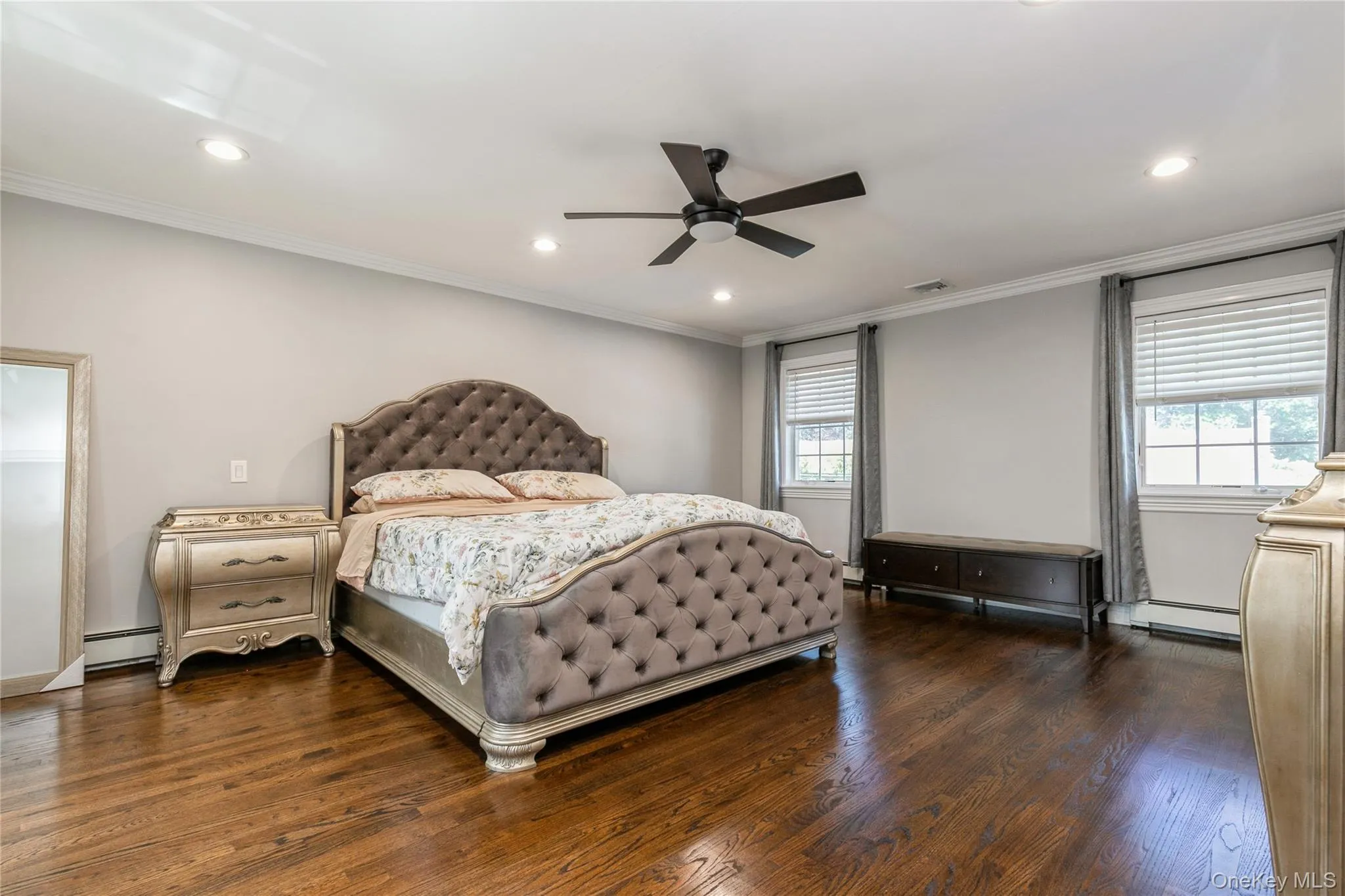 Bedroom with multiple windows, ornamental molding, dark wood-type flooring, recessed lighting, and a baseboard radiator Bedroom with multiple windows, ornamental molding, dark wood-type flooring, recessed lighting, and a baseboard radiator