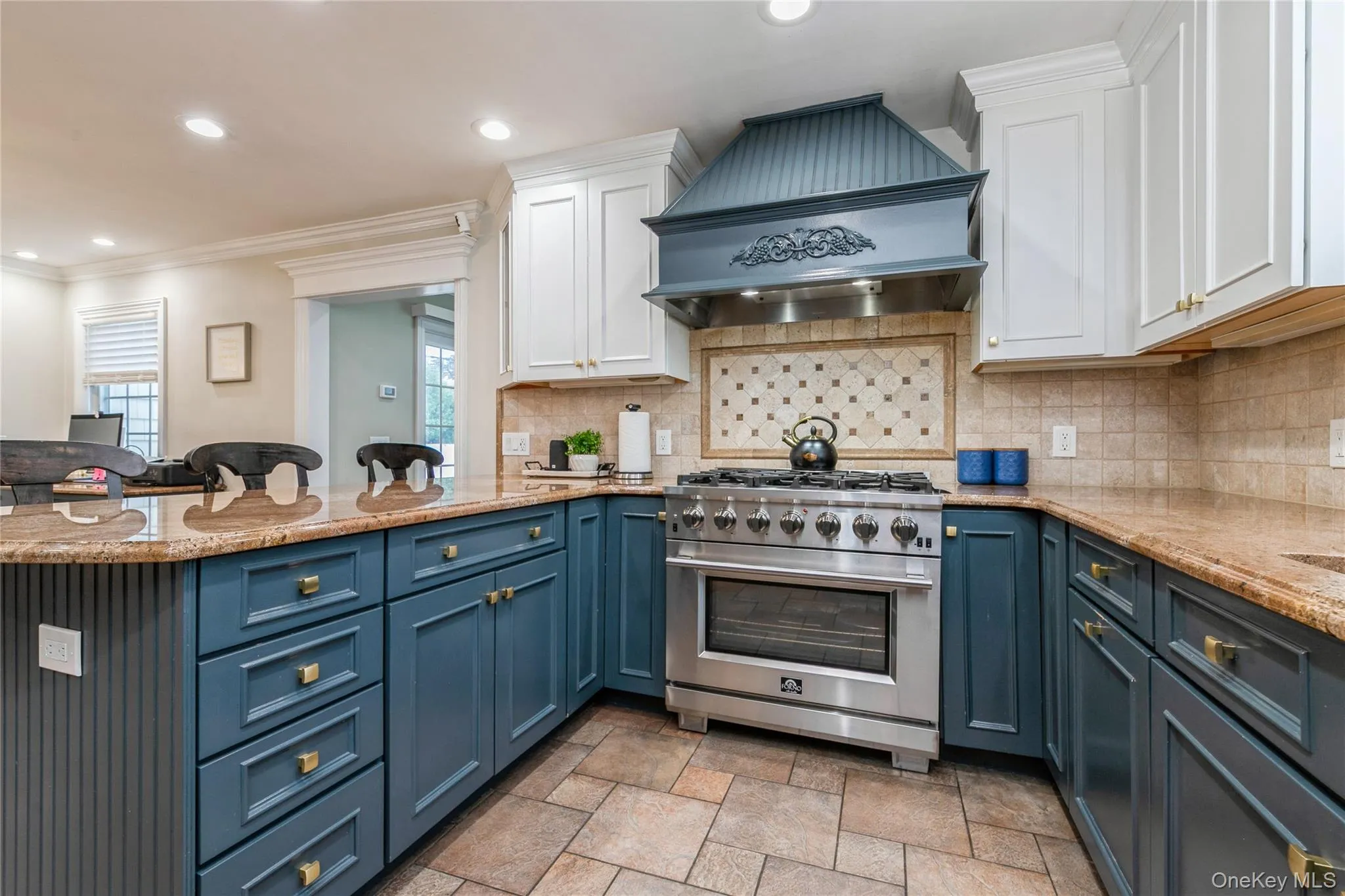 Kitchen featuring white cabinetry, high end stainless steel range oven, custom range hood, blue cabinets, and ornamental molding Kitchen featuring white cabinetry, high end stainless steel range oven, custom range hood, blue cabinets, and ornamental molding