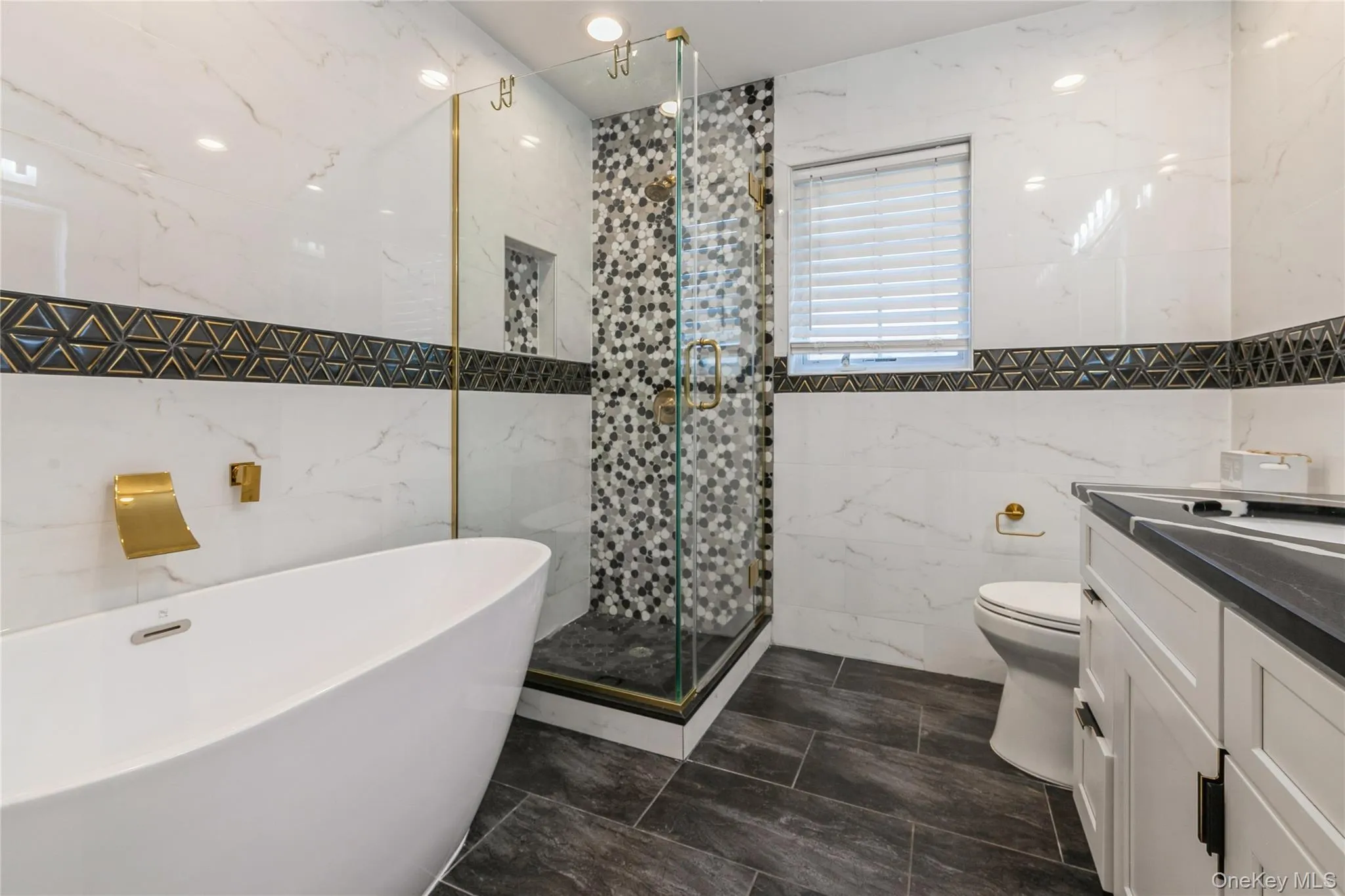Full bath featuring tile walls, a freestanding tub, vanity, and a stall shower Full bath featuring tile walls, a freestanding tub, vanity, and a stall shower