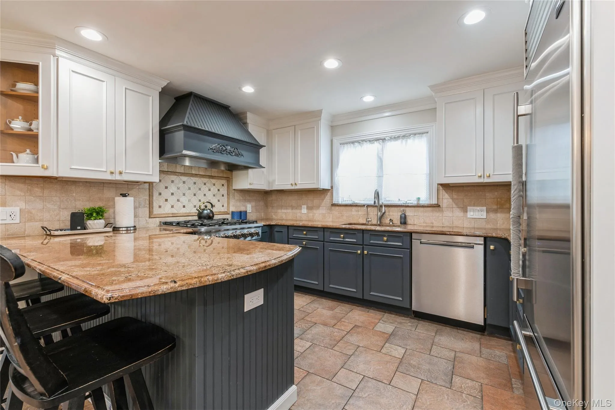Kitchen with a peninsula, white cabinetry, premium range hood, appliances with stainless steel finishes, and recessed lighting Kitchen with a peninsula, white cabinetry, premium range hood, appliances with stainless steel finishes, and recessed lighting