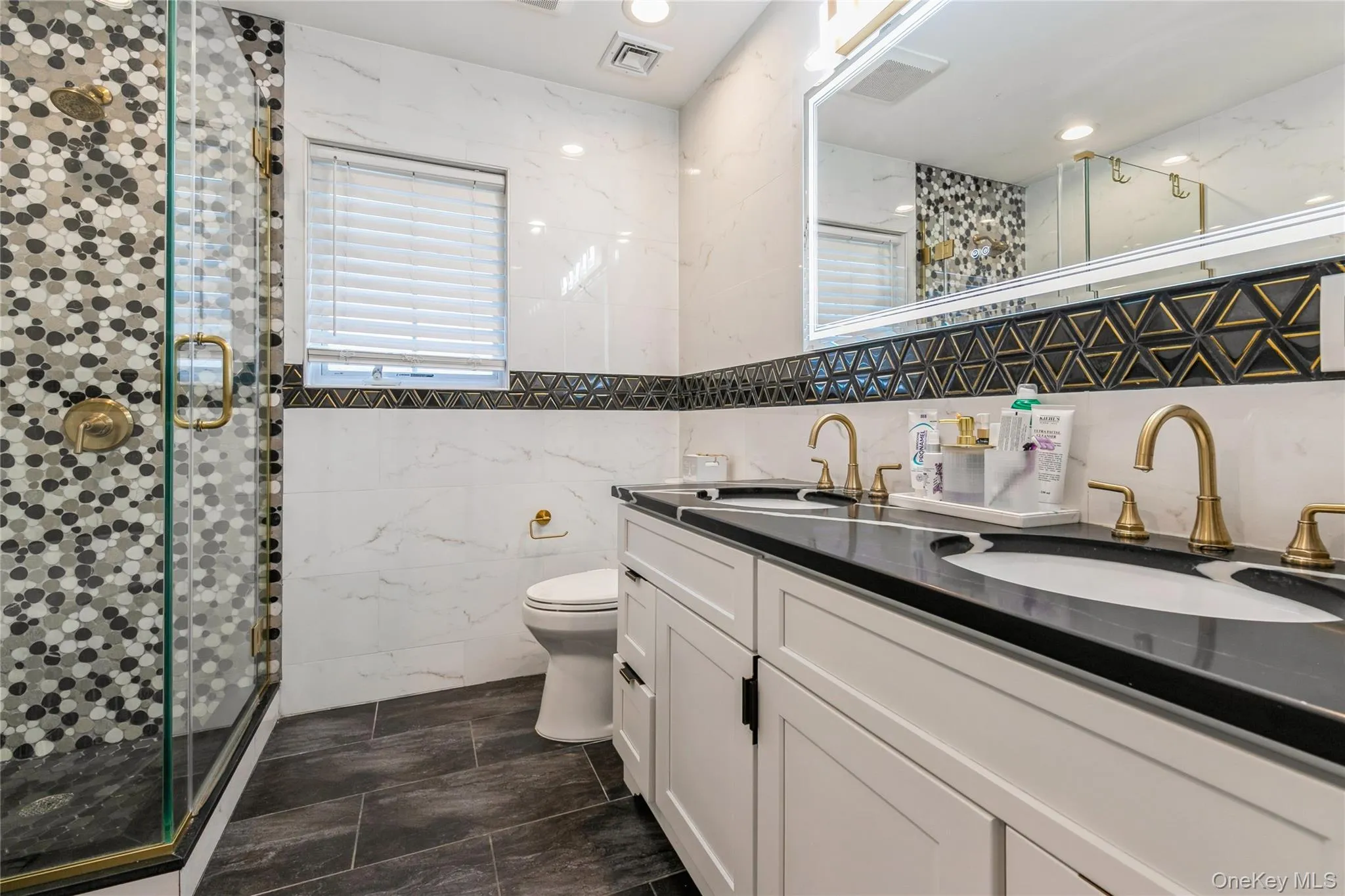 Full bathroom with tile walls, a stall shower, and double vanity Full bathroom with tile walls, a stall shower, and double vanity