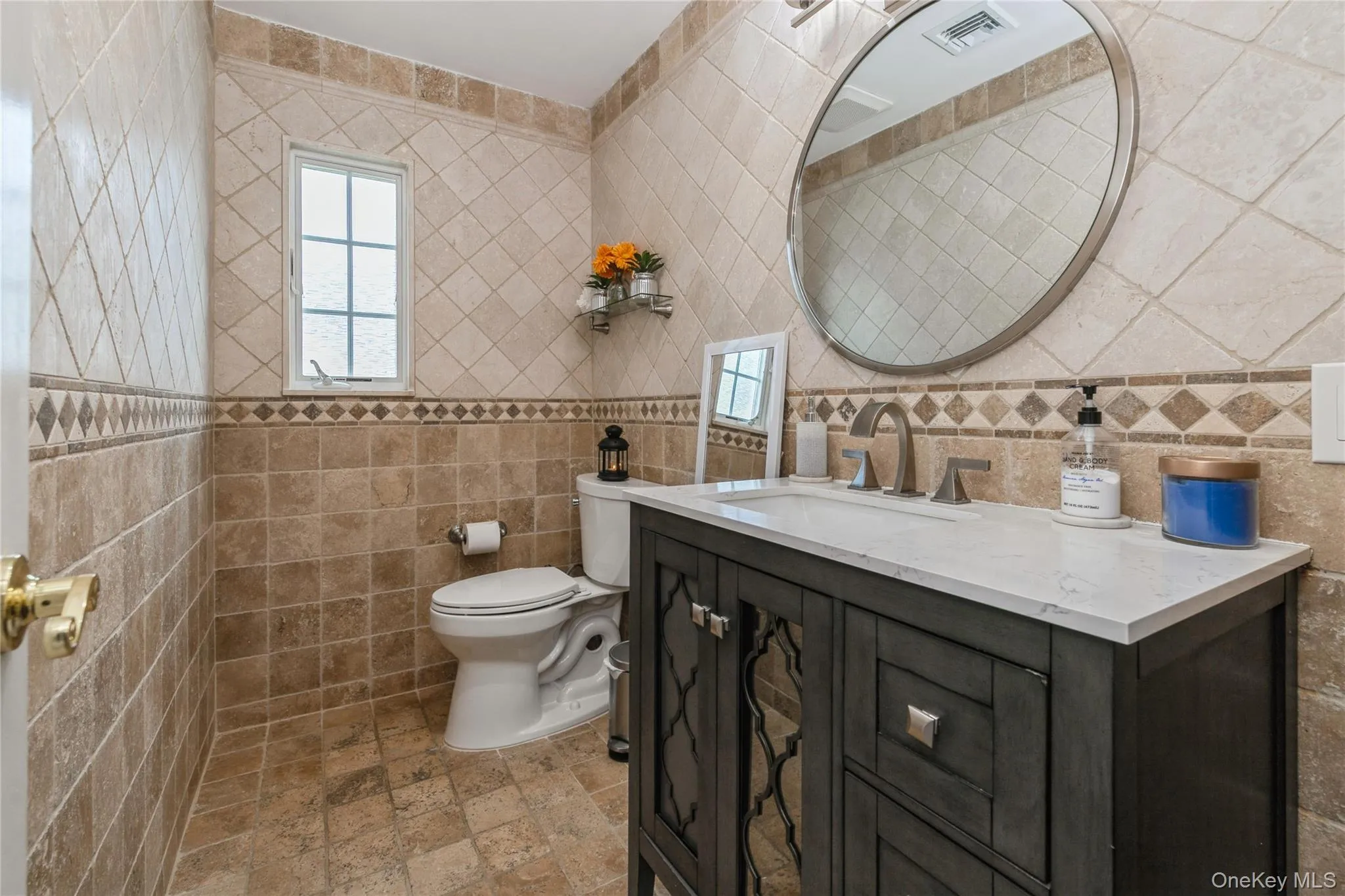 Bathroom featuring tile walls, vanity, and stone finish flooring Bathroom featuring tile walls, vanity, and stone finish flooring