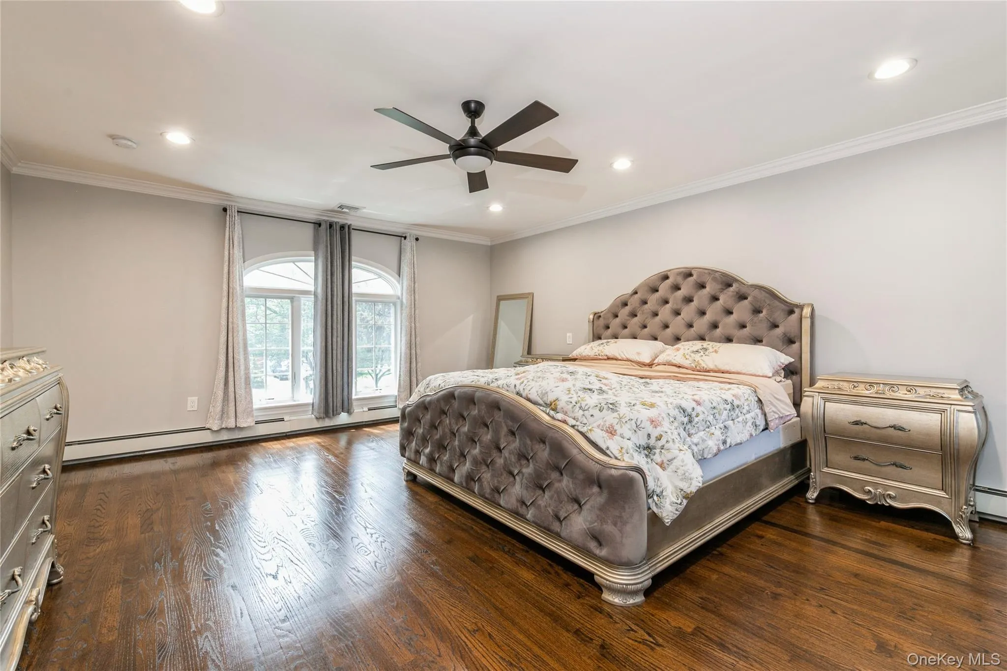 Bedroom with a baseboard radiator, recessed lighting, dark wood-style floors, ornamental molding, and a ceiling fan Bedroom with a baseboard radiator, recessed lighting, dark wood-style floors, ornamental molding, and a ceiling fan