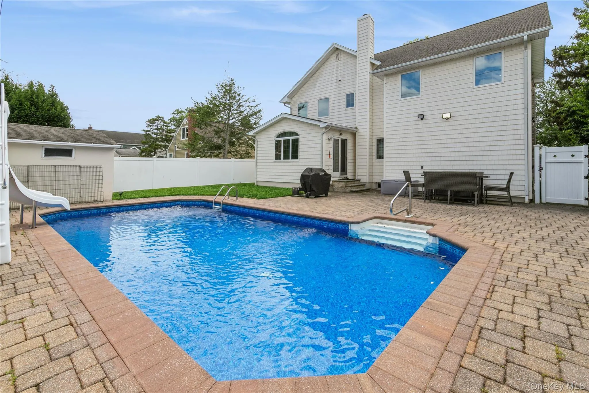 View of swimming pool featuring a water slide, a patio area, entry steps, a fenced backyard, and grilling area View of swimming pool featuring a water slide, a patio area, entry steps, a fenced backyard, and grilling area