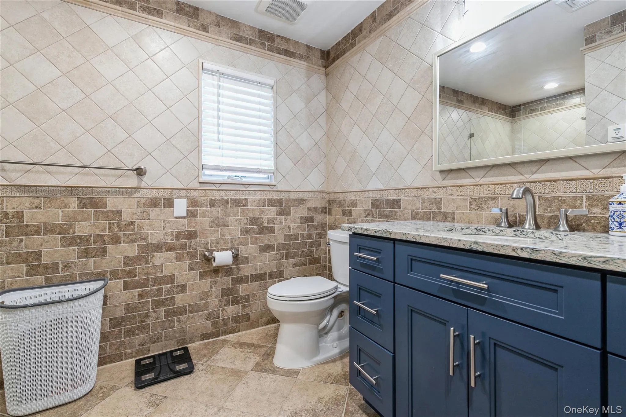 Bathroom with vanity, tile walls, and stone finish floors Bathroom with vanity, tile walls, and stone finish floors