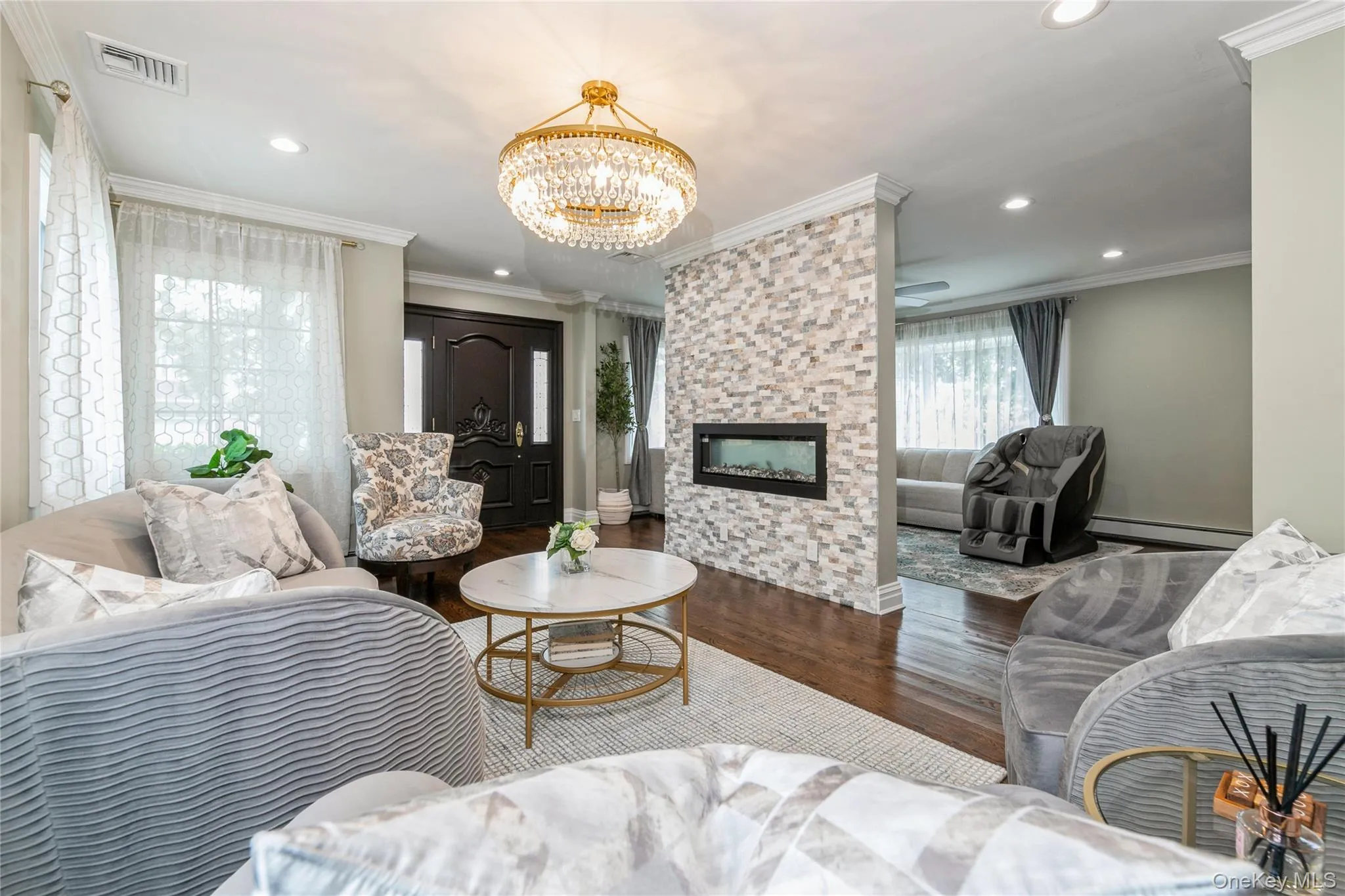 Living room featuring wood finished floors, a chandelier, recessed lighting, ornamental molding, and a fireplace Living room featuring wood finished floors, a chandelier, recessed lighting, ornamental molding, and a fireplace