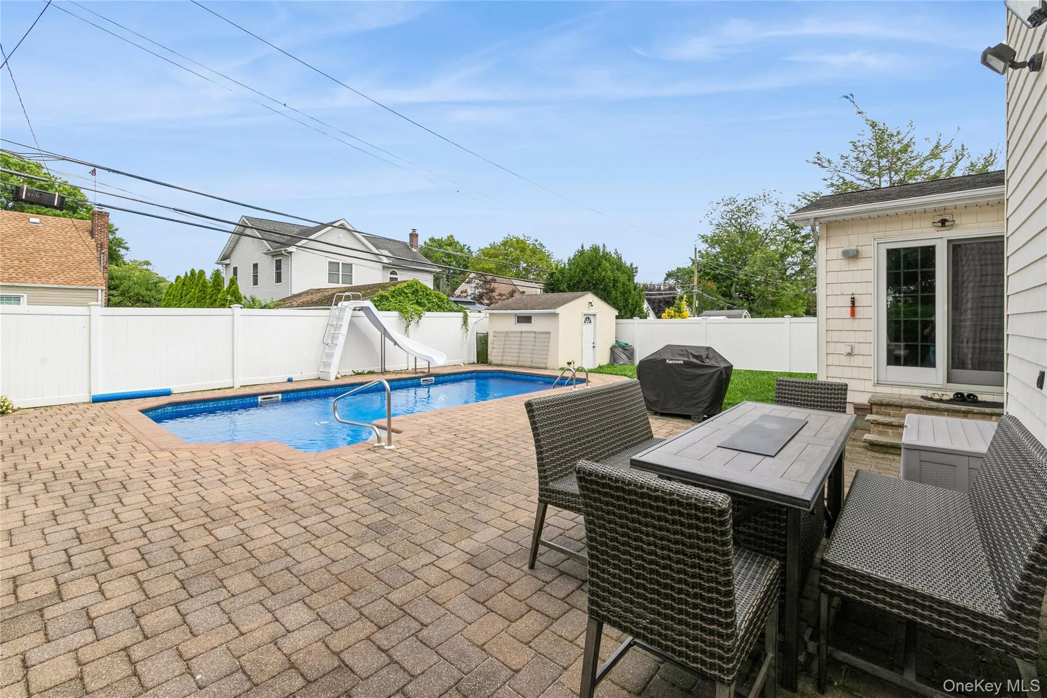 View of pool featuring a water slide, a patio, a fenced backyard, a shed, and area for grilling View of pool featuring a water slide, a patio, a fenced backyard, a shed, and area for grilling