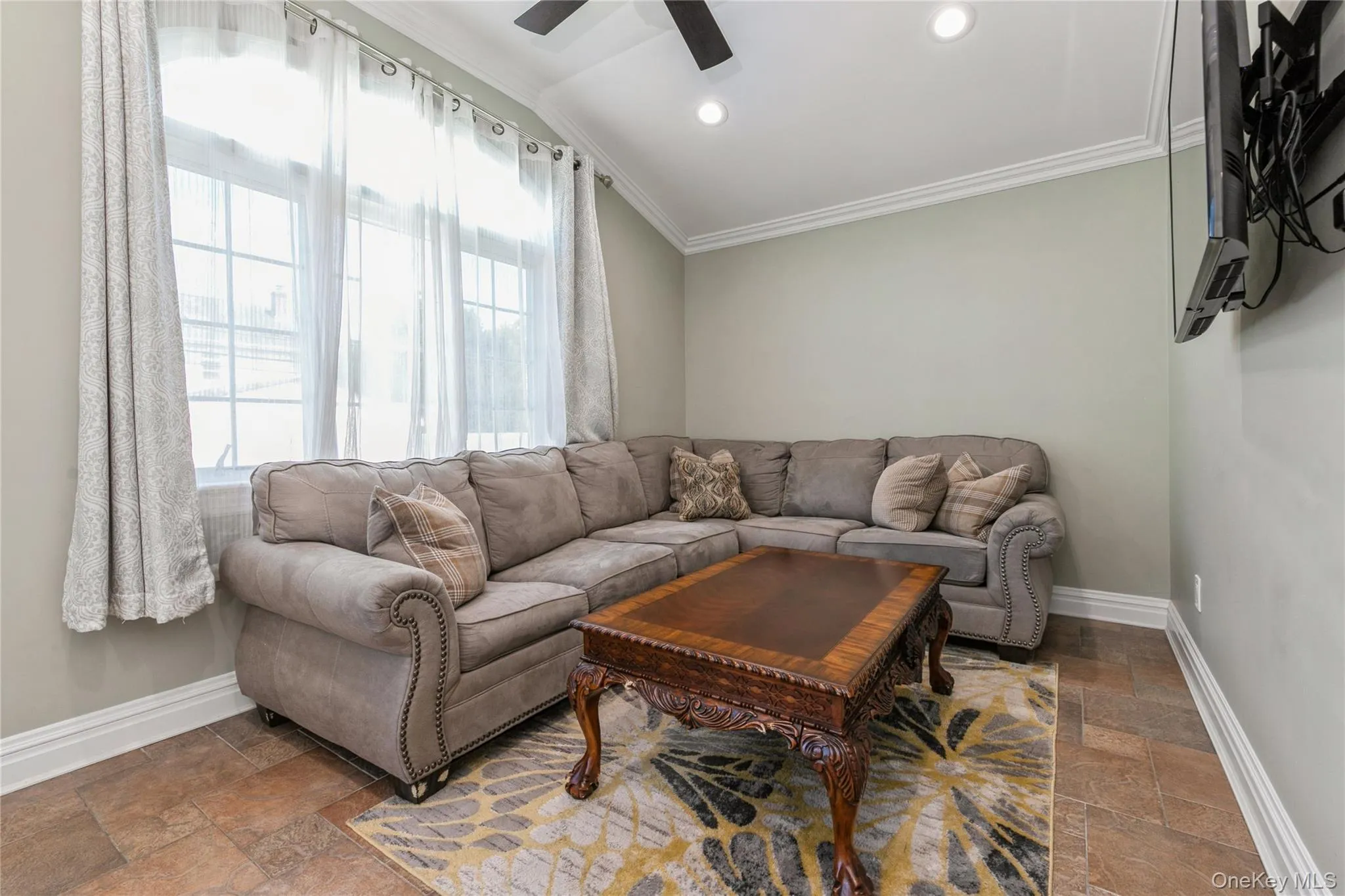 Living room featuring stone tile floors, ornamental molding, a ceiling fan, and recessed lighting Living room featuring stone tile floors, ornamental molding, a ceiling fan, and recessed lighting