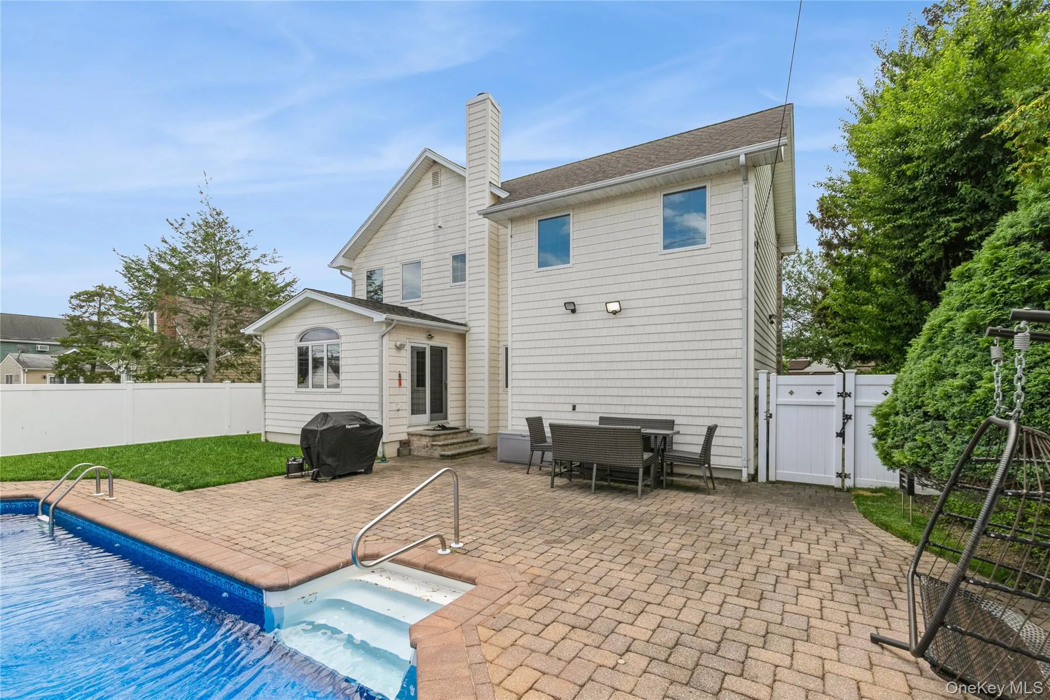 Back of house featuring a gate, a patio, a fenced backyard, and a chimney Back of house featuring a gate, a patio, a fenced backyard, and a chimney